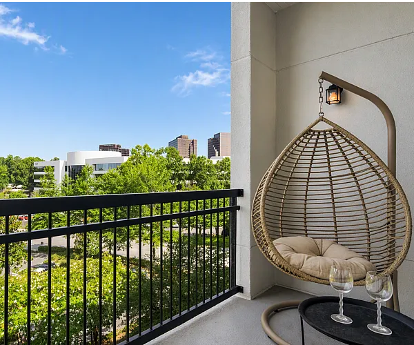 Charming balcony view with a cozy hanging chair and cityscape backdrop ideal for relaxation.
