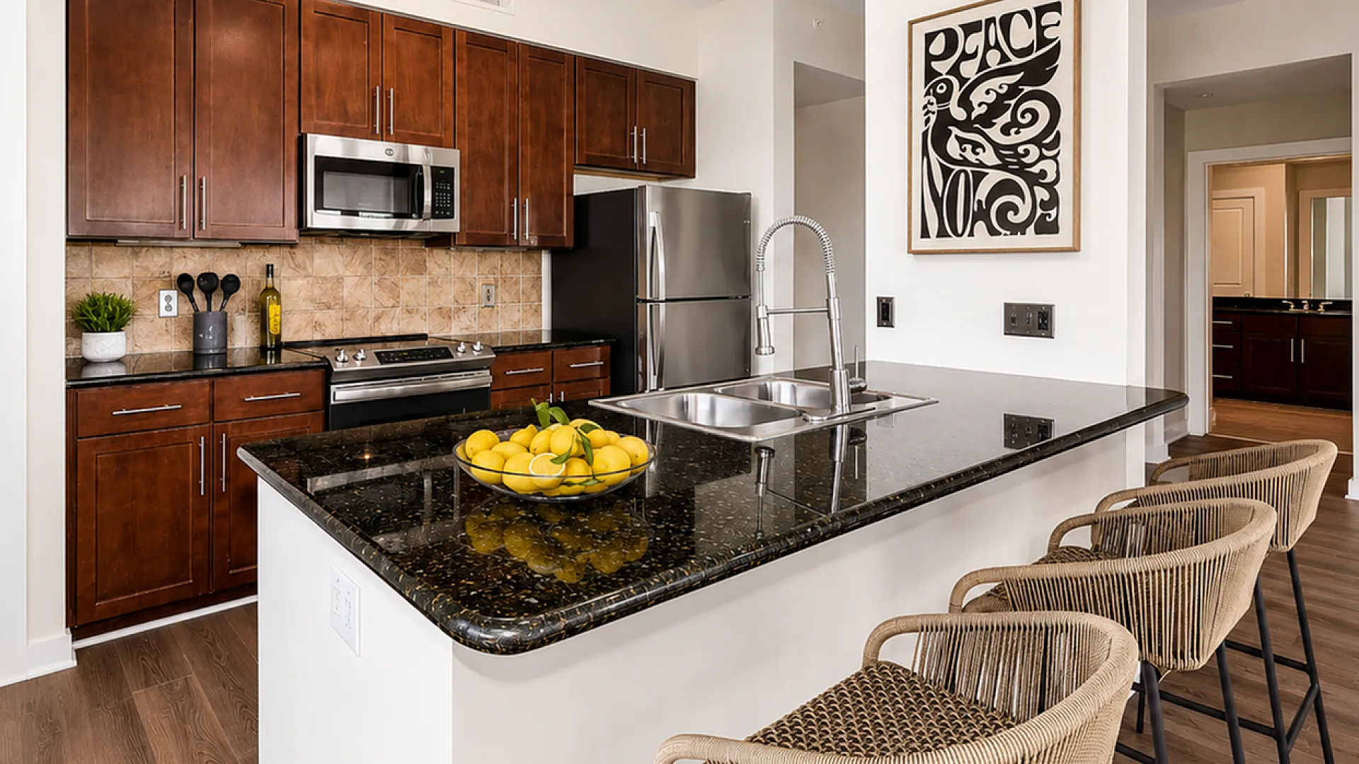 Modern kitchen with elegant dark wood cabinets, granite countertops, and stainless steel appliances featuring a stylish breakfast bar and stools.