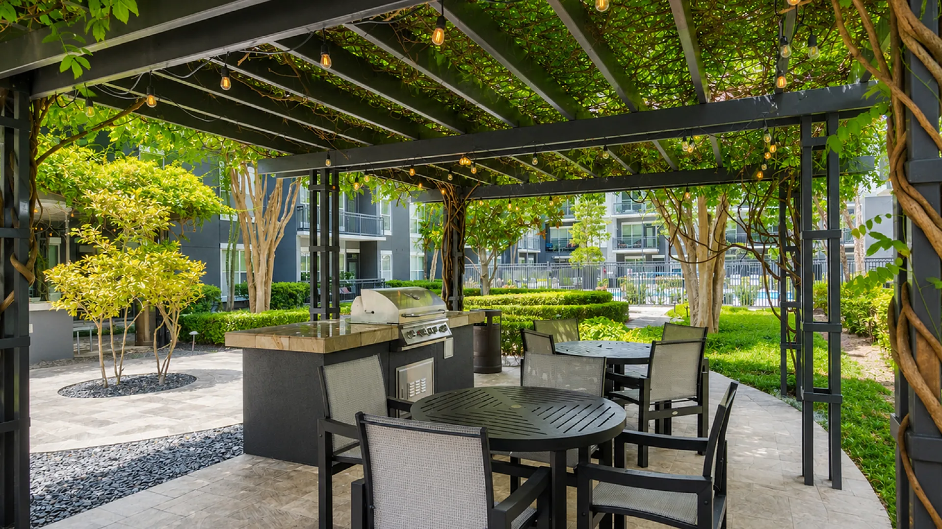 Charming outdoor patio with a lush garden, featuring a stylish pergola, modern barbecue grill, and elegant seating area.
