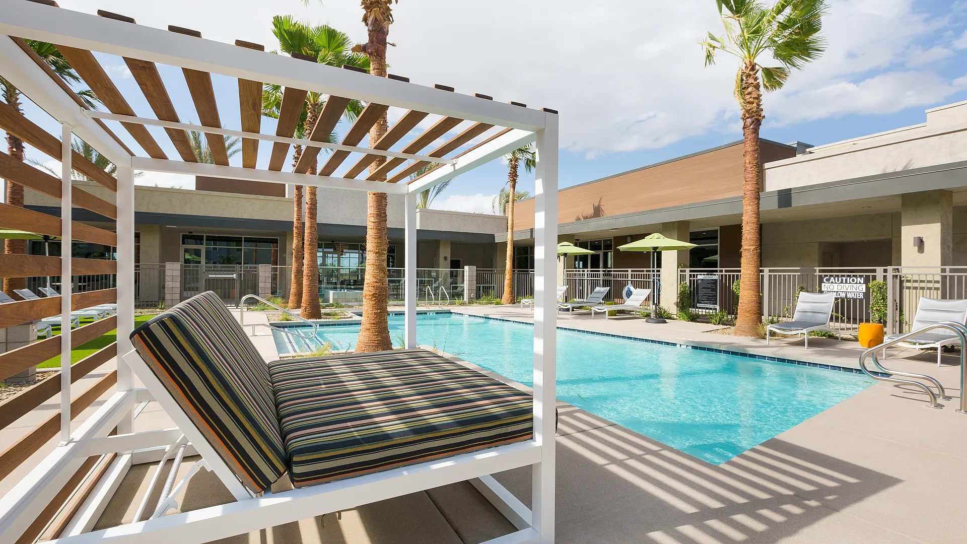 Luxurious outdoor pool area with sleek cabanas and palm trees under a bright sky, ideal for relaxation.