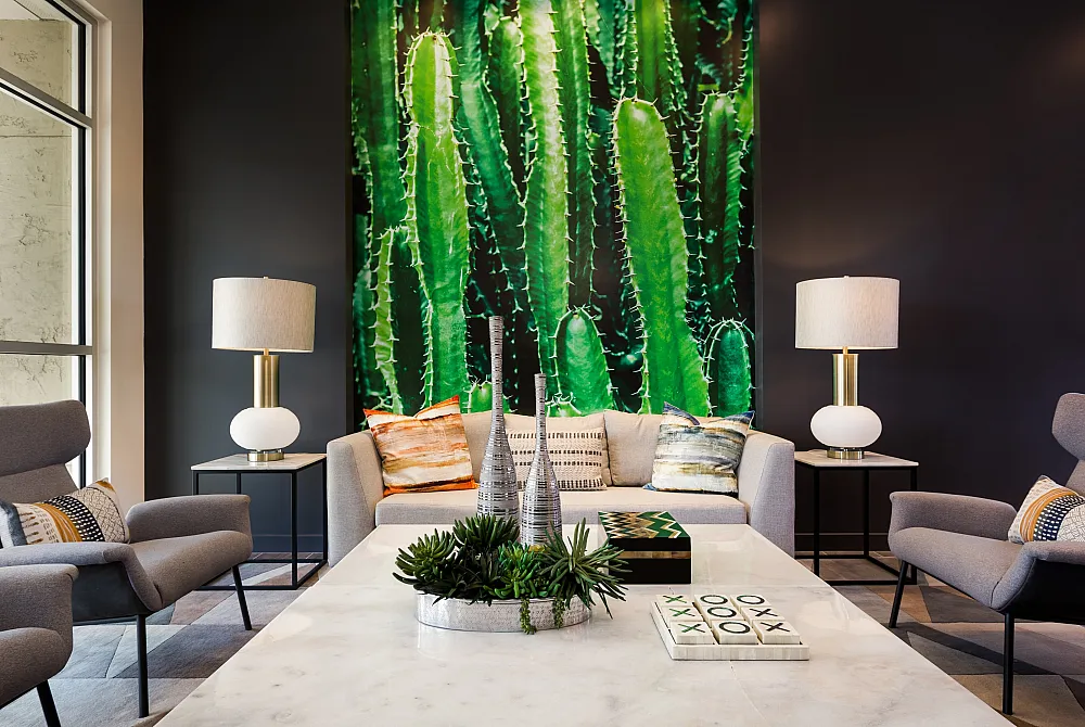 Bright and modern living room featuring a cozy gray sofa, vibrant cactus wall art, elegant lamps, and chic decorative accents.