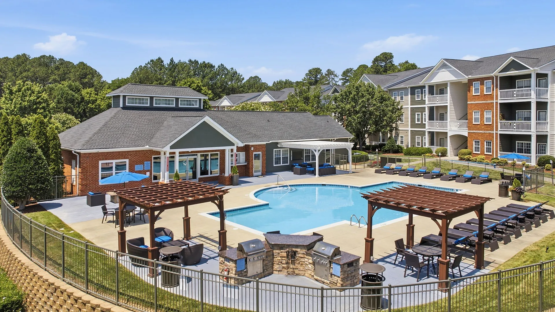 Luxurious apartment community featuring a sparkling pool, stylish pergolas, outdoor grills, and spacious lounging area.