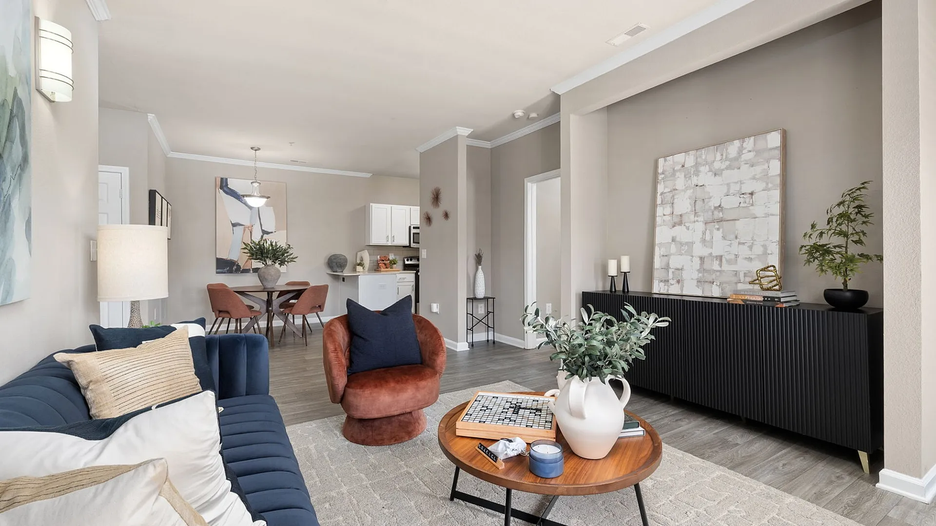 Modern living area featuring a stylish navy sofa, cozy seating, and a chic dining space by the kitchen; perfect for entertaining in elegance.