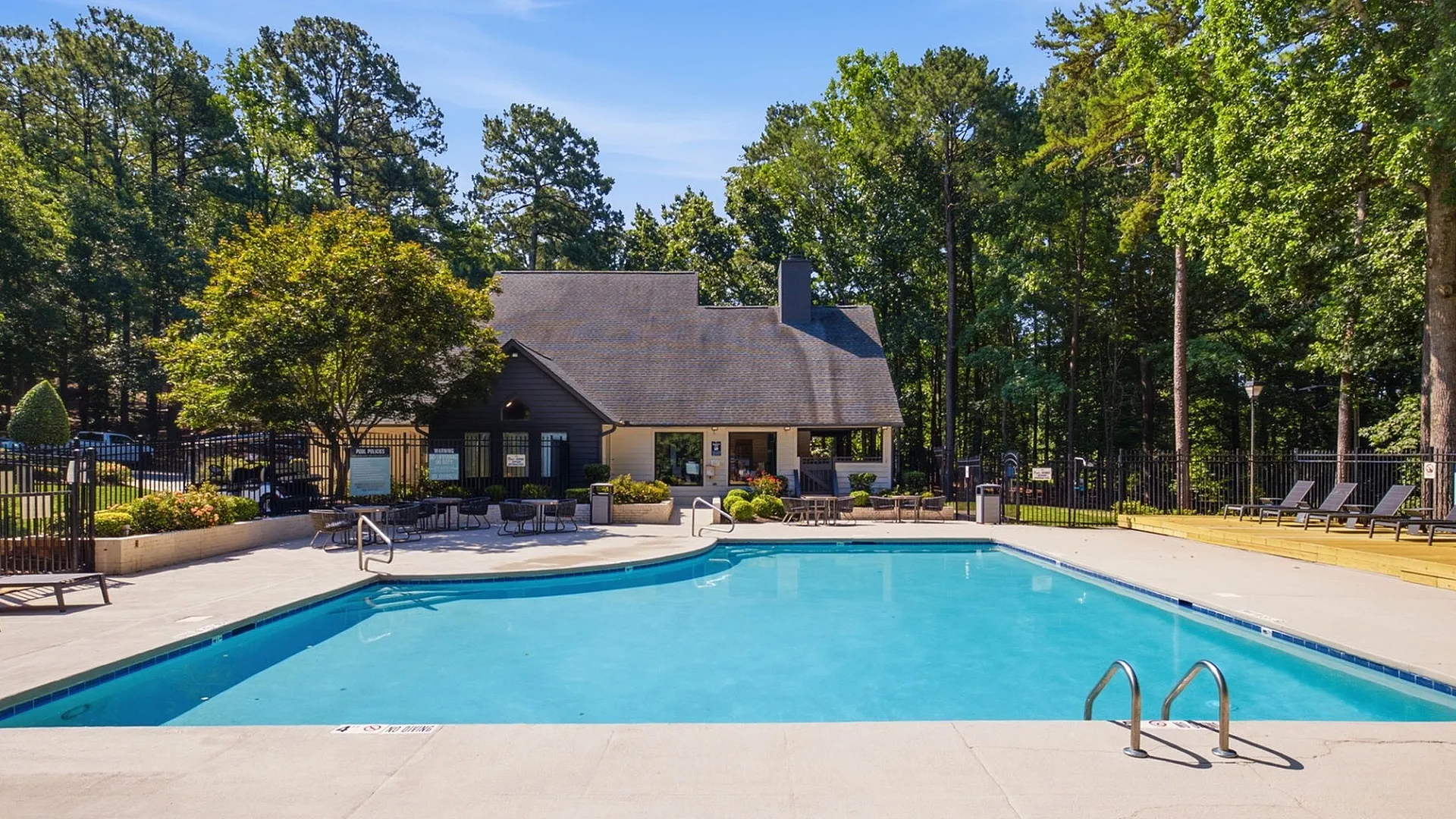 Charming apartment community with a sparkling pool, surrounded by lush greenery and modern amenities for relaxation.