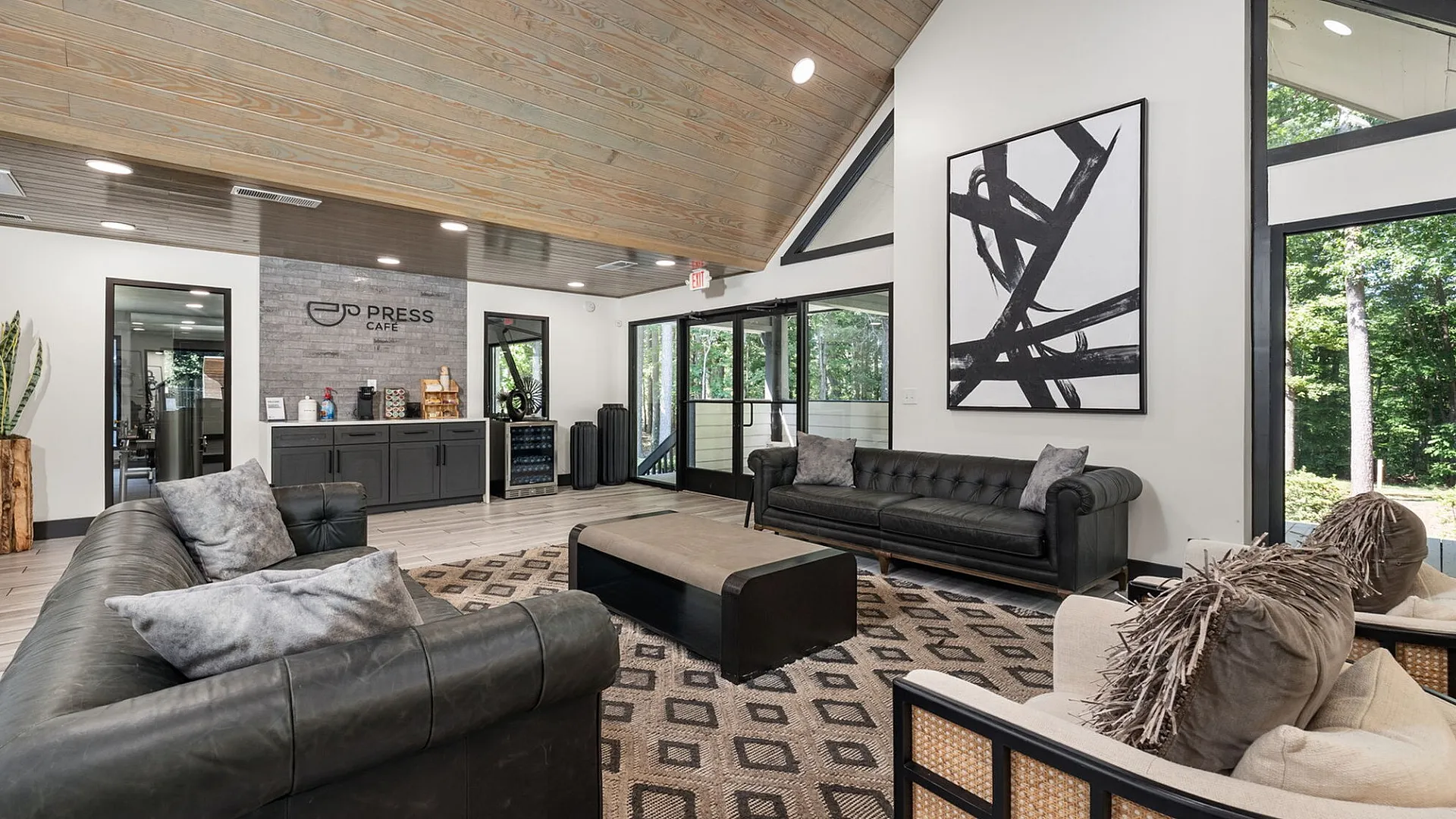 Modern and inviting lounge area featuring plush seating, natural light, and a chic cafe corner with woodland views.