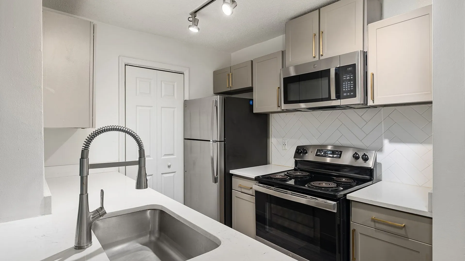 Modern kitchen with sleek stainless steel appliances, elegant cabinetry, and a stylish gooseneck faucet.