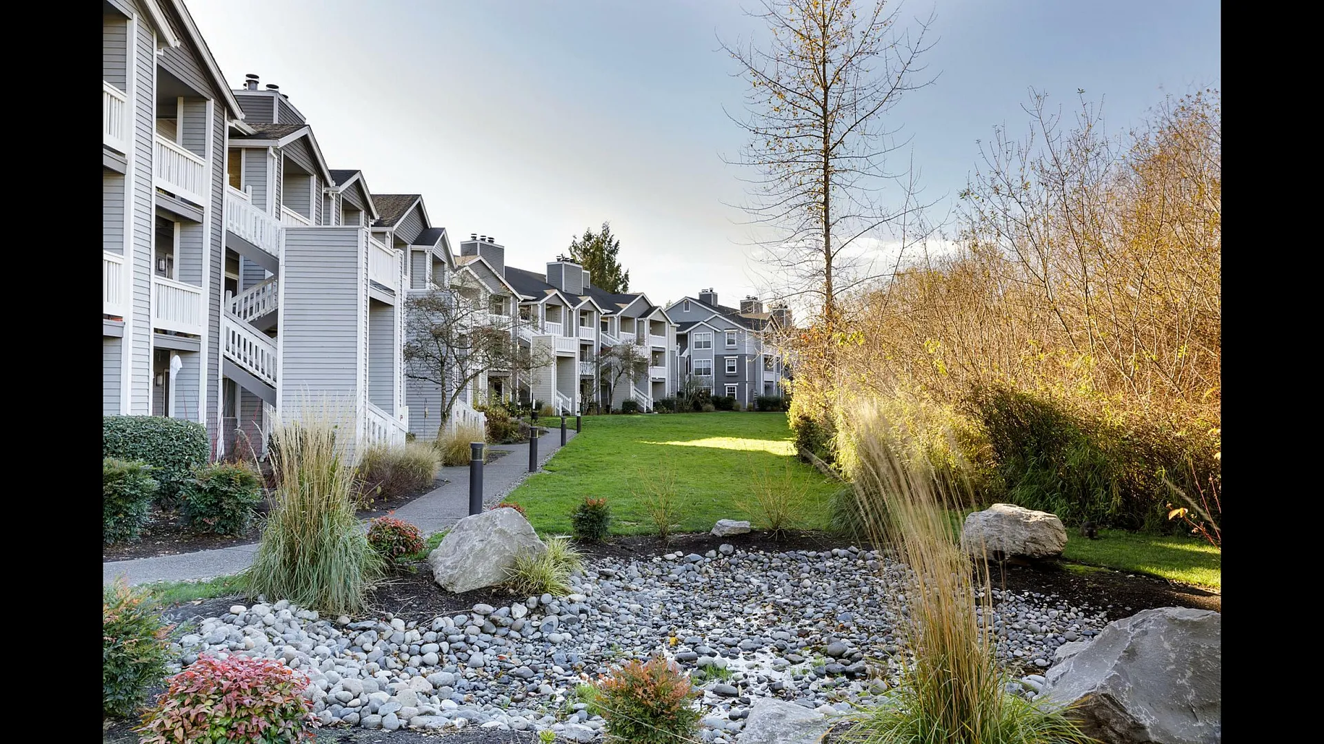 Charming apartment complex with modern design, nestled amidst vibrant landscaping and serene green spaces.
