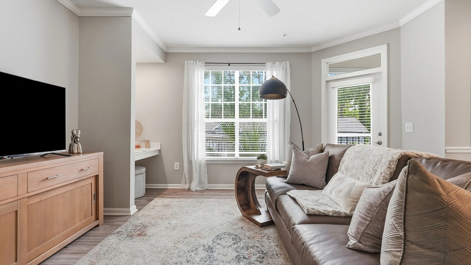 Bright and inviting living room featuring a cozy leather sofa, elegant decor, and large windows for ample natural light.