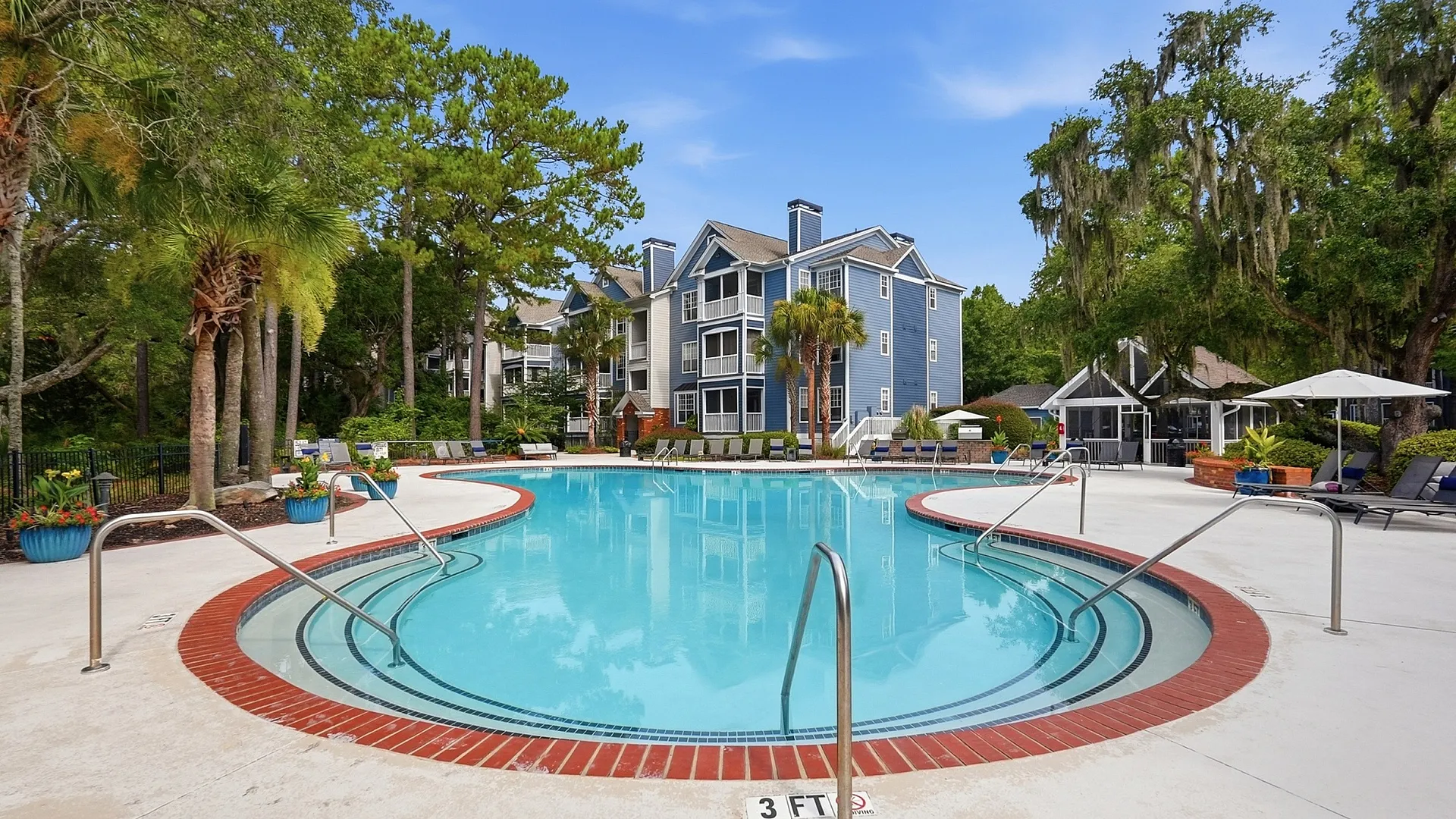 Inviting community pool surrounded by lush greenery and modern apartment buildings, showcasing a perfect blend of resort-style living and natural beauty.