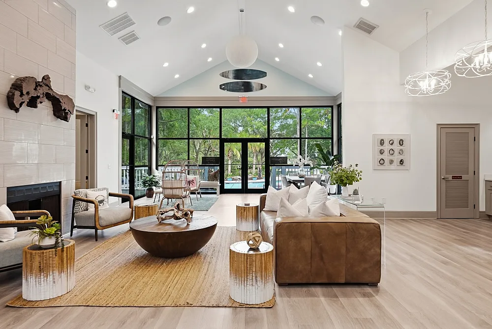 Elegant living room with vaulted ceiling, large windows, modern decor, and lush garden view.