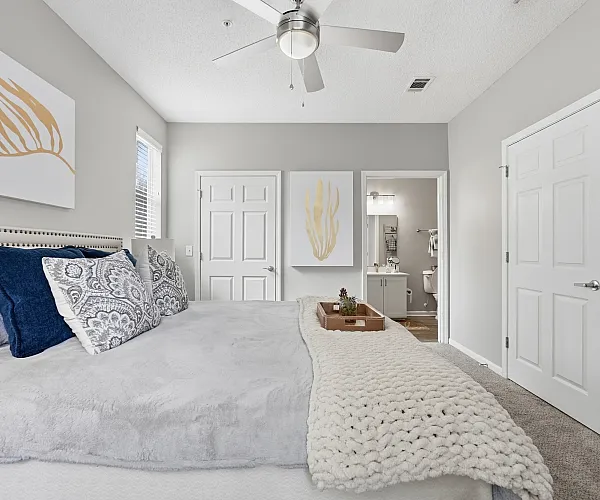Inviting bedroom with plush bedding, elegant artwork, and seamless access to a modern en-suite bathroom, perfect for relaxation.