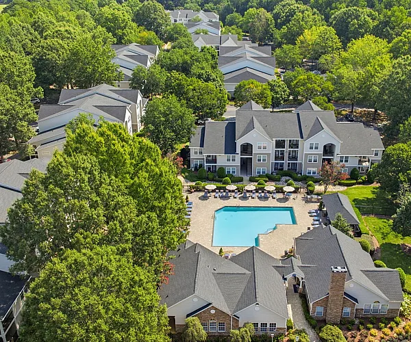 Charming apartment complex surrounded by lush greenery, featuring a refreshing central swimming pool and inviting patios.