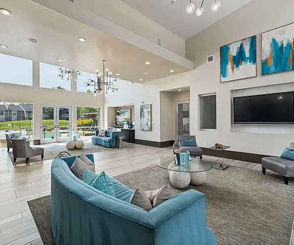 Elegant living space with modern decor and large windows, featuring stylish seating, a flat-screen TV, and vibrant artwork.