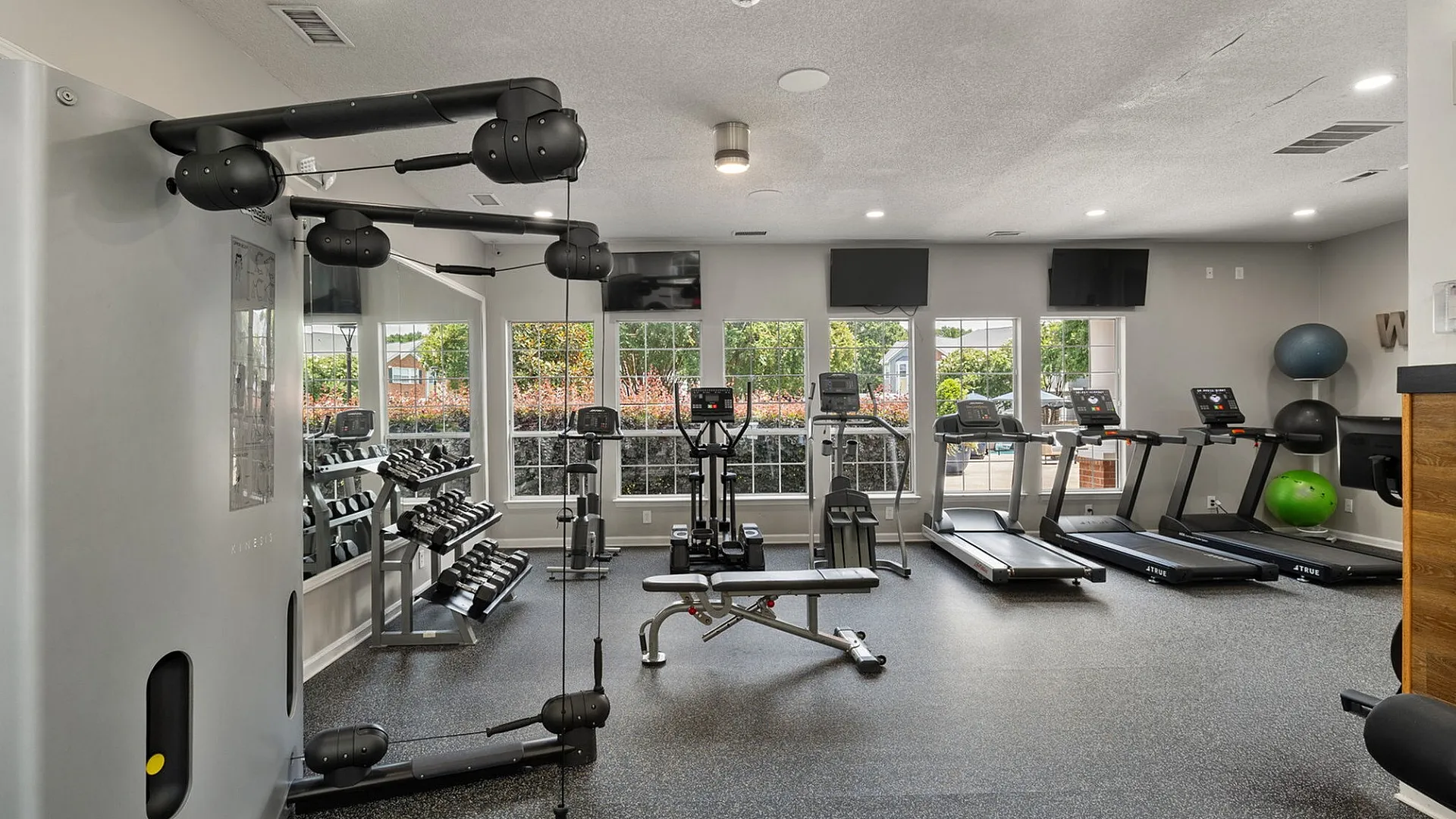 Modern fitness center with state-of-the-art exercise equipment, treadmills, and large windows offering natural light.