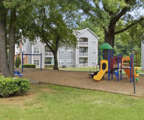 Inviting apartment complex with modern playground and lush green spaces, perfect for family living and outdoor enjoyment.