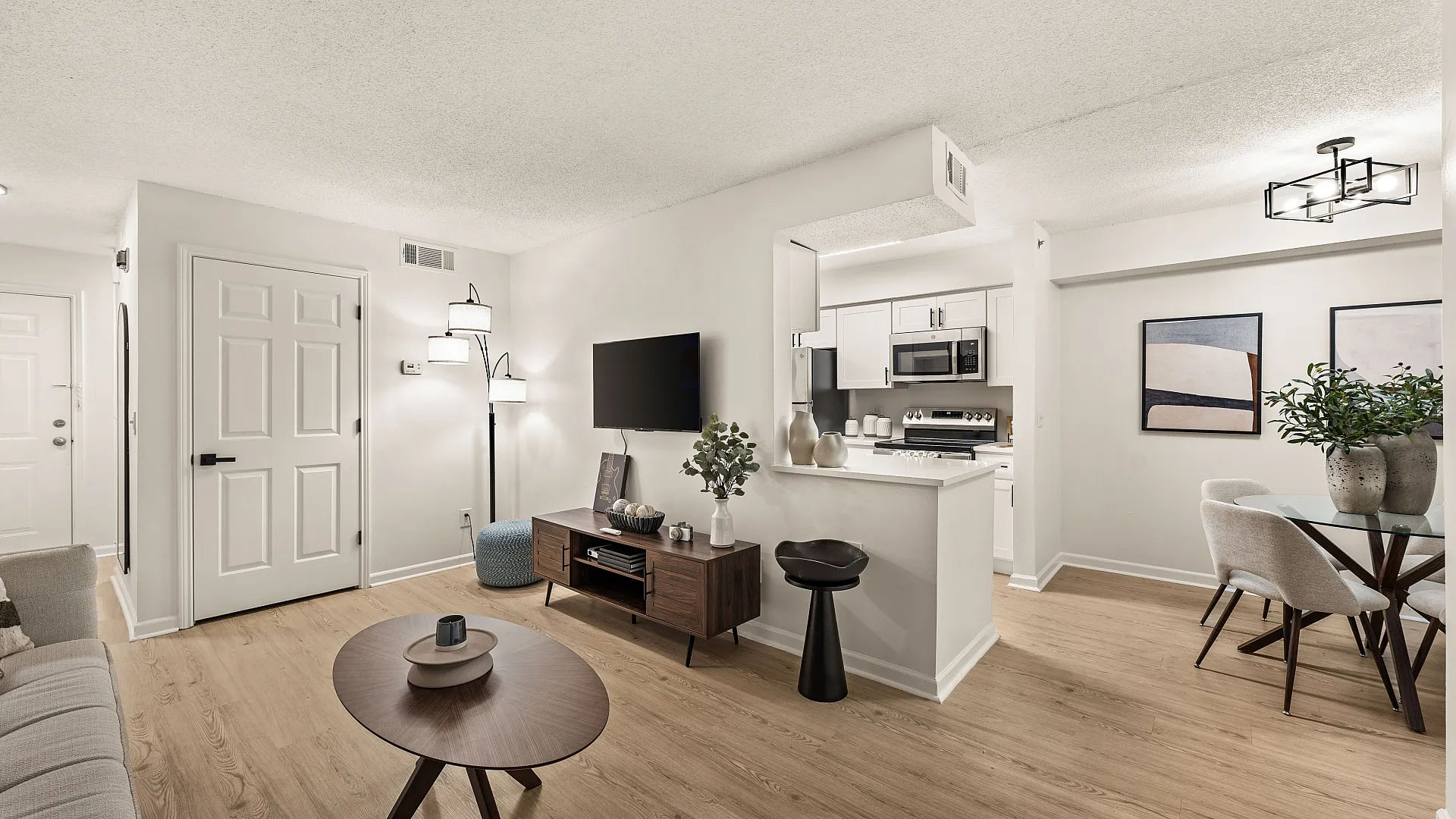 Modern open living space featuring a sleek kitchen, cozy sitting area, and stylish dining nook with elegant decor.