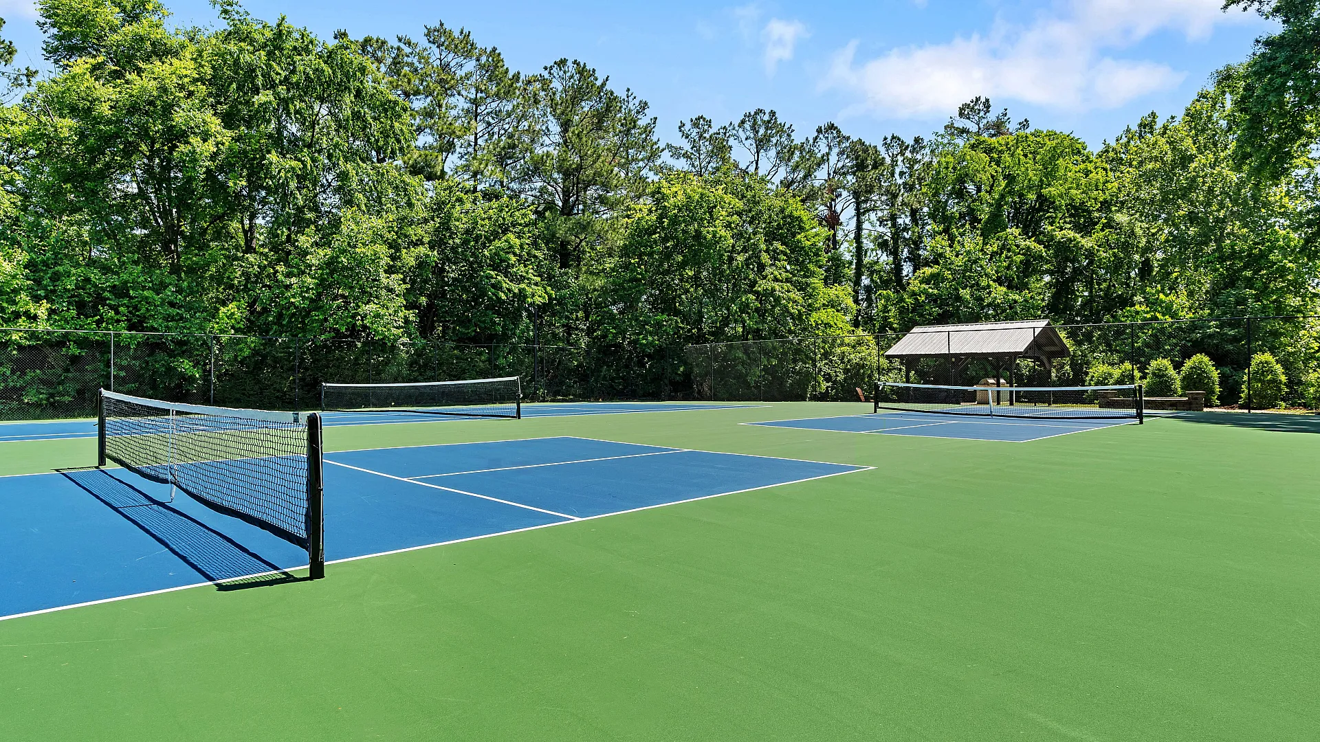 Beautiful outdoor tennis court surrounded by lush greenery, perfect for relaxation and recreation.