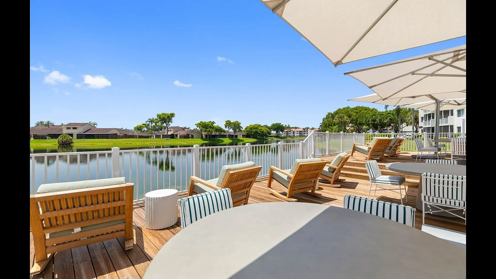 Chic lakeside deck with comfortable lounge chairs and large umbrellas, offering serene water views and a perfect relaxation spot.