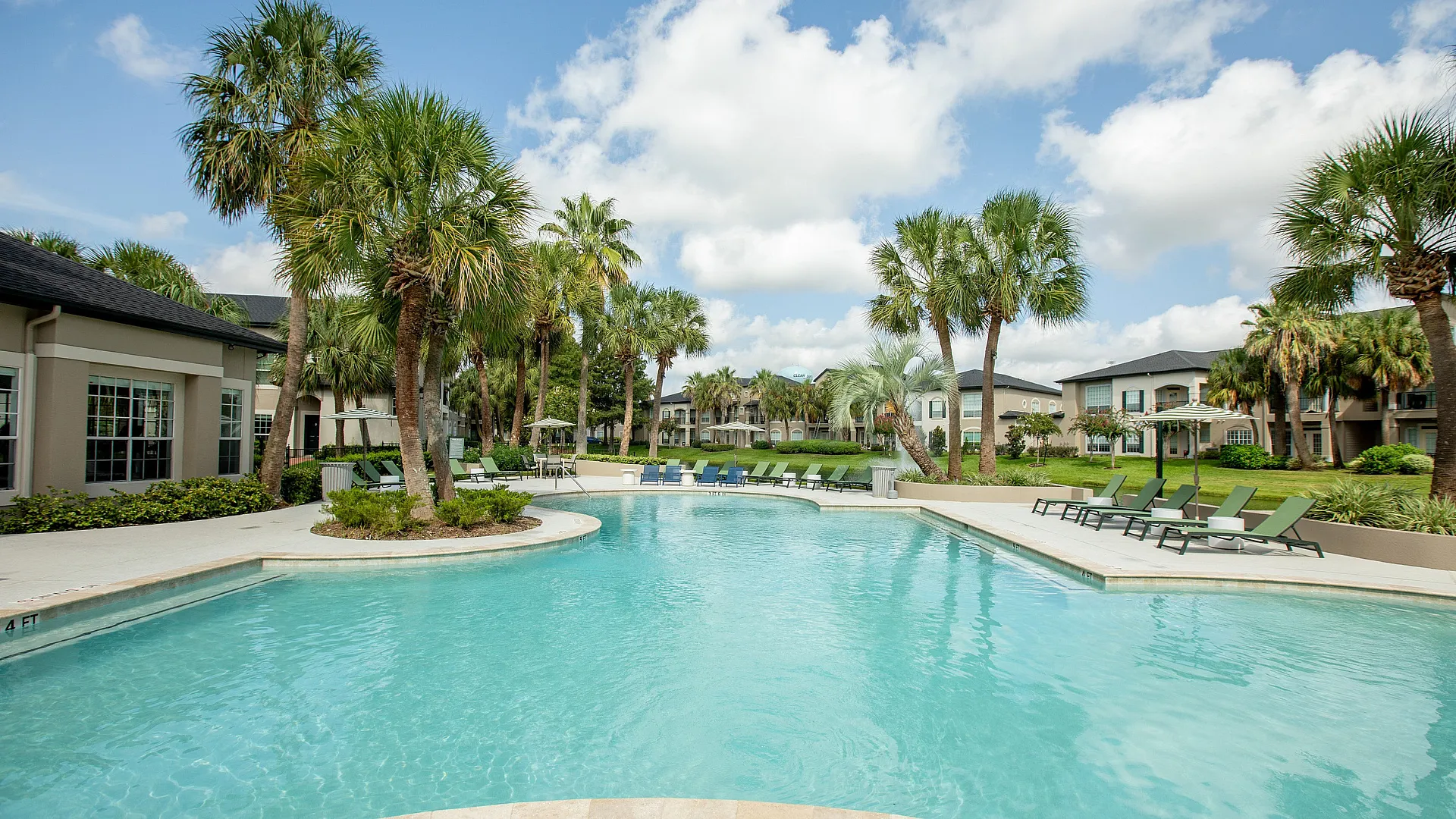 Lounge chairs overlooking a sparkling pond and palm trees