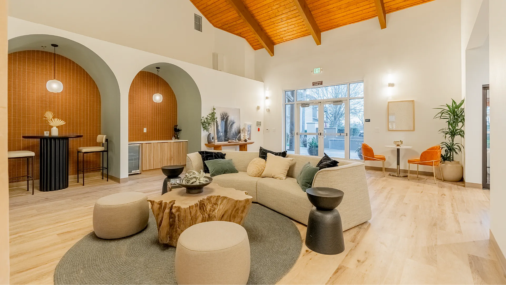Inviting modern lounge area with a stylish curved sofa, rustic wooden coffee table, and chic archways, perfect for relaxation and social gatherings.