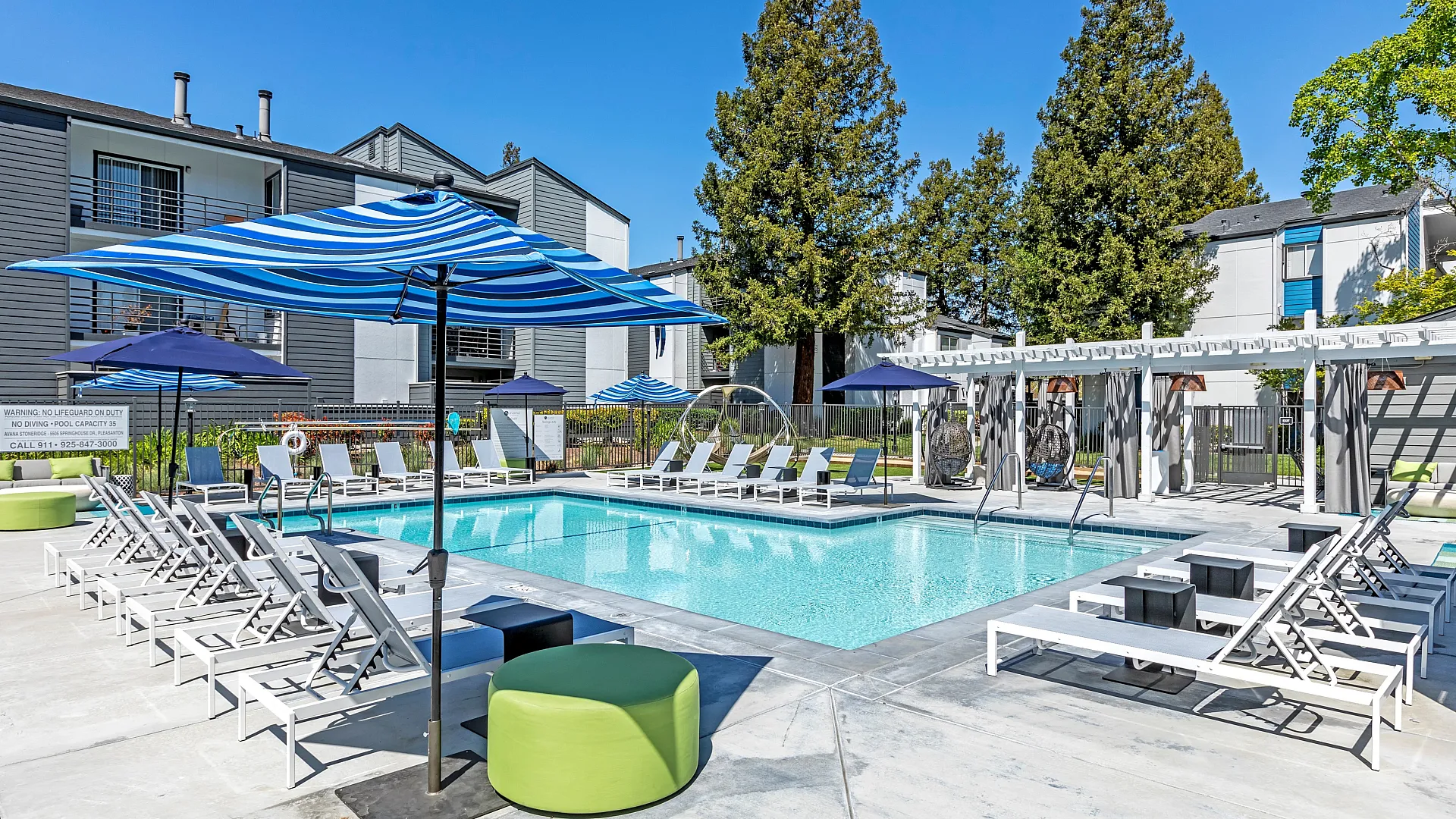 Inviting outdoor pool area with stylish lounge chairs and vibrant umbrellas, perfect for relaxation and socializing.