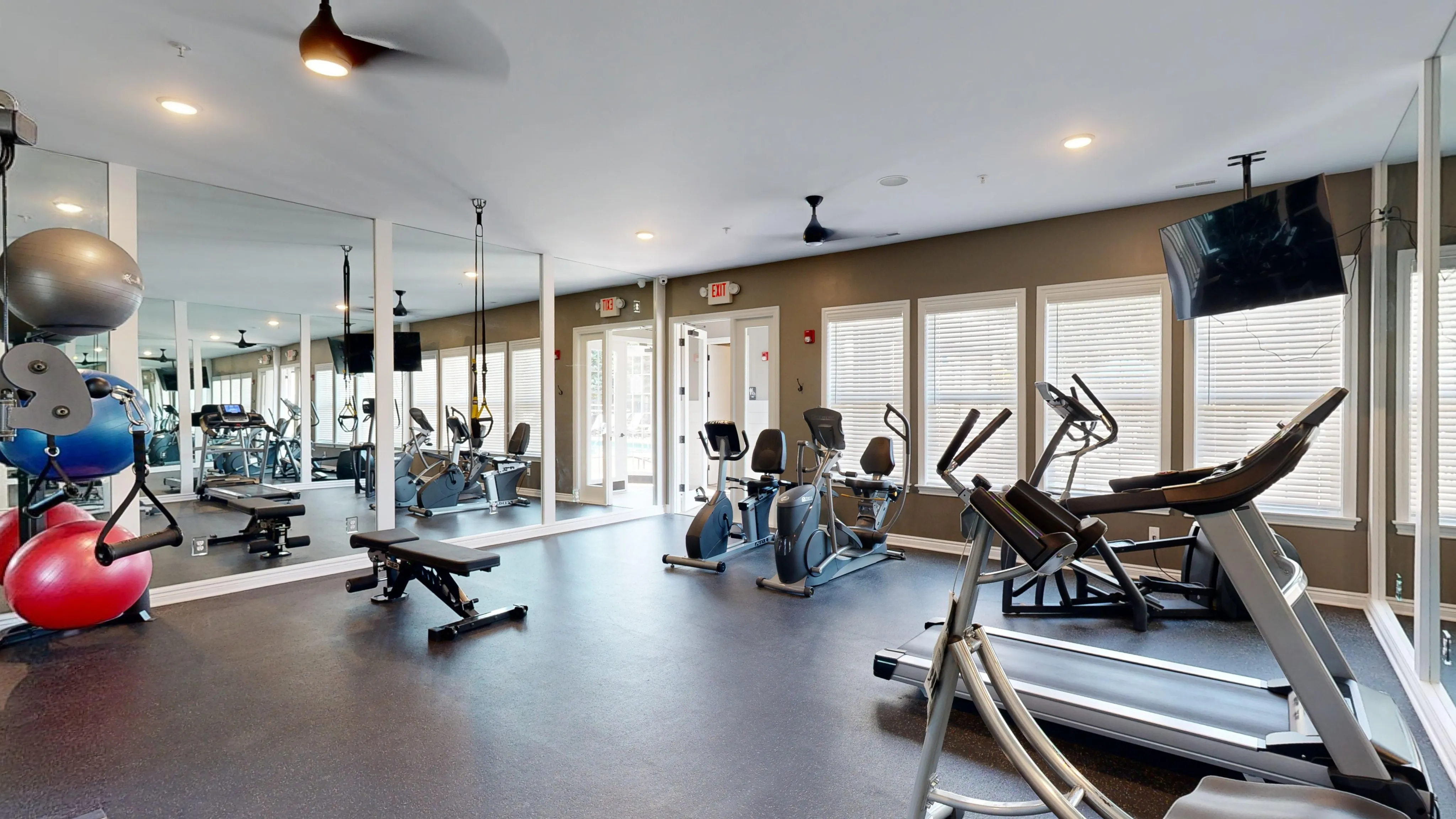 Modern fitness center featuring state-of-the-art equipment, mirrored walls, natural lighting, and sleek design for an invigorating workout experience.