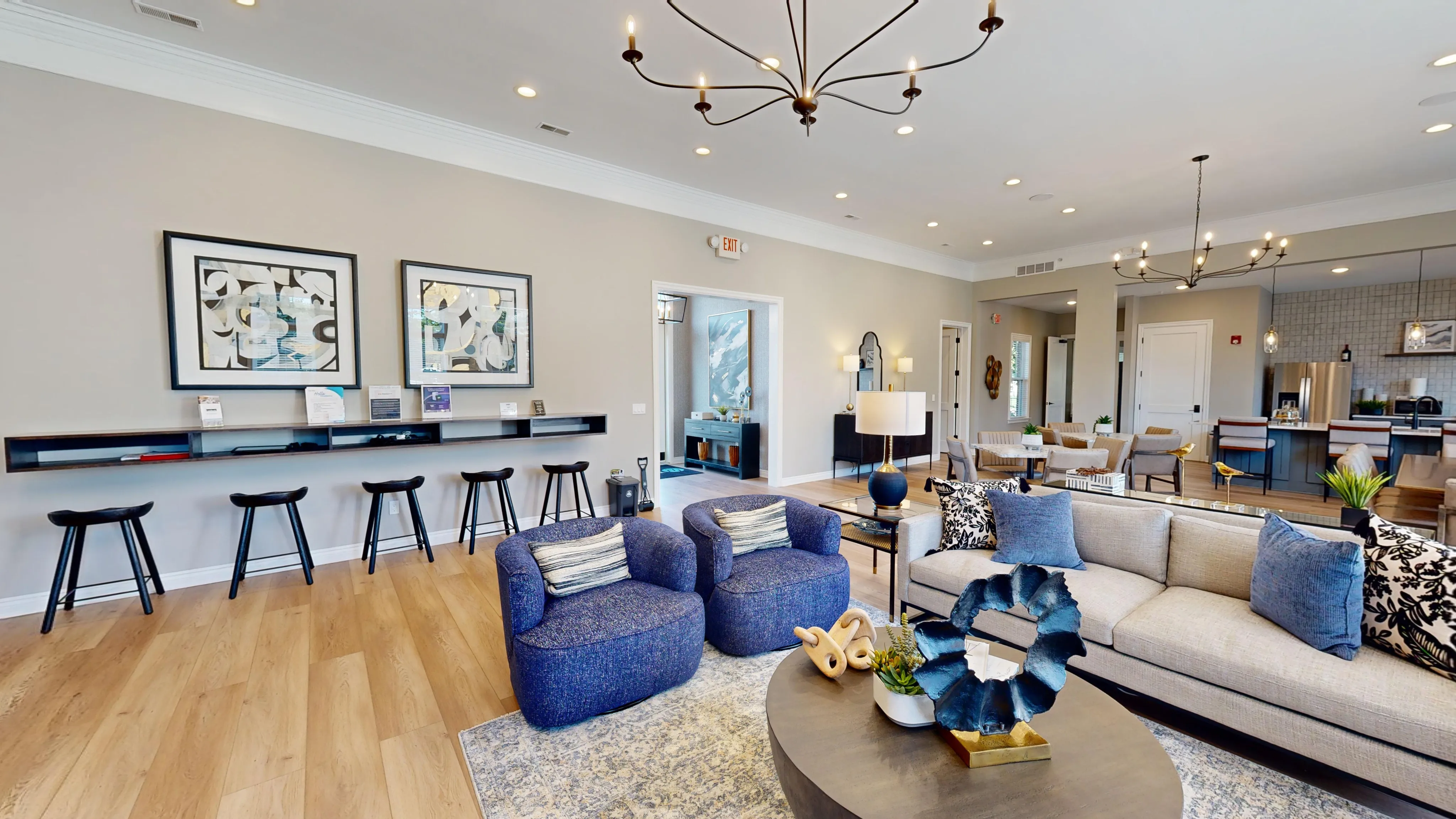 Elegant open-concept living area featuring modern decor with plush seating, chic lighting fixtures, and a stylish kitchen in the background.
