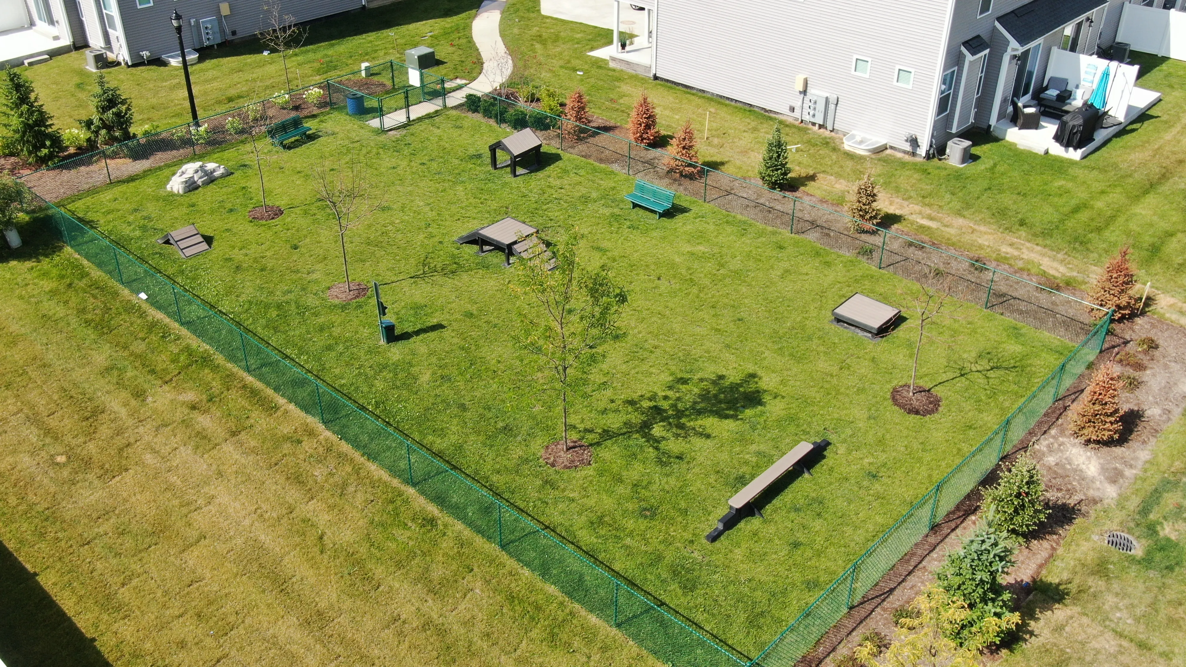 Spacious community dog park with agility equipment and lush greenery, perfect for pet-friendly living.