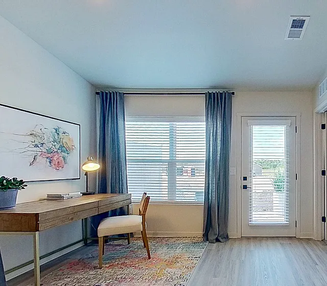 Bright and inviting home office with a wooden desk, elegant decor, and a large mirror reflecting natural light.