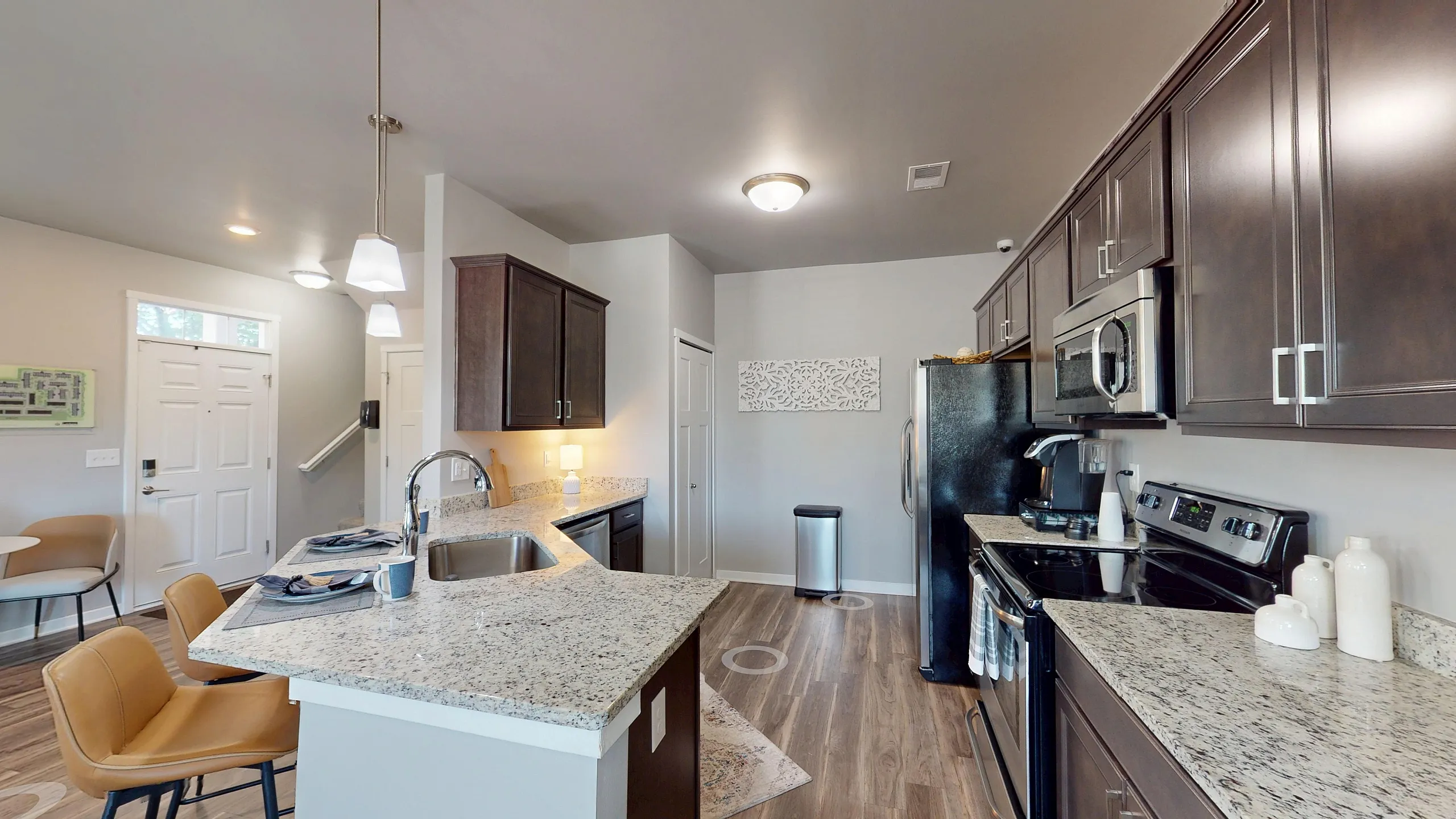 Modern kitchen with sleek granite countertops, dark wood cabinetry, and stainless steel appliances, offering a stylish and functional cooking space.