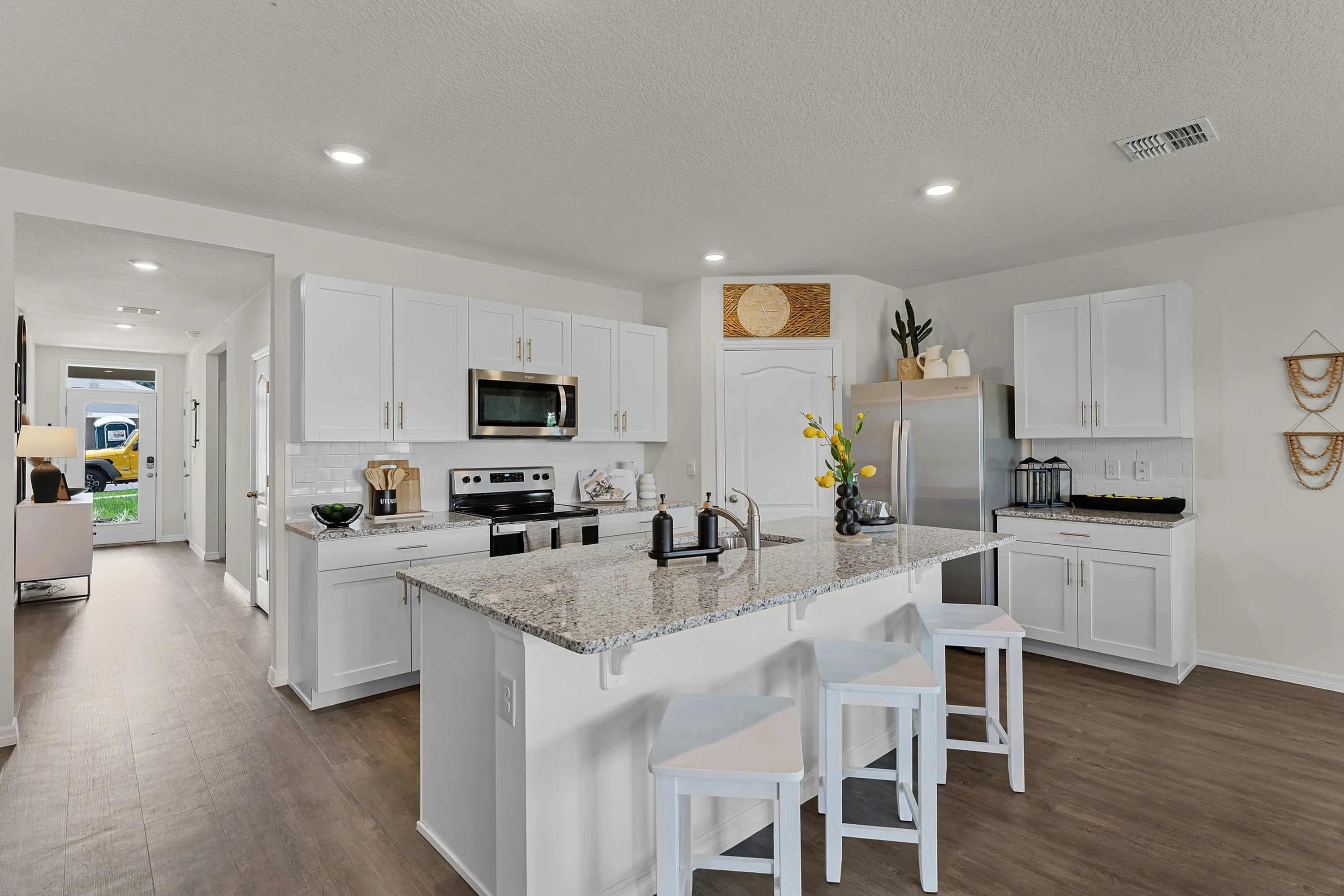 Modern kitchen with island seating, granite countertops, and stainless steel appliances.
