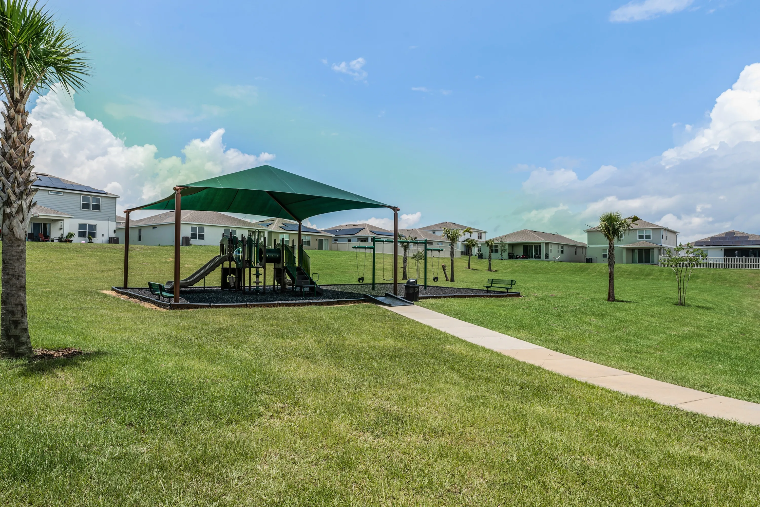Shaded playground nestled in wide-open green space.