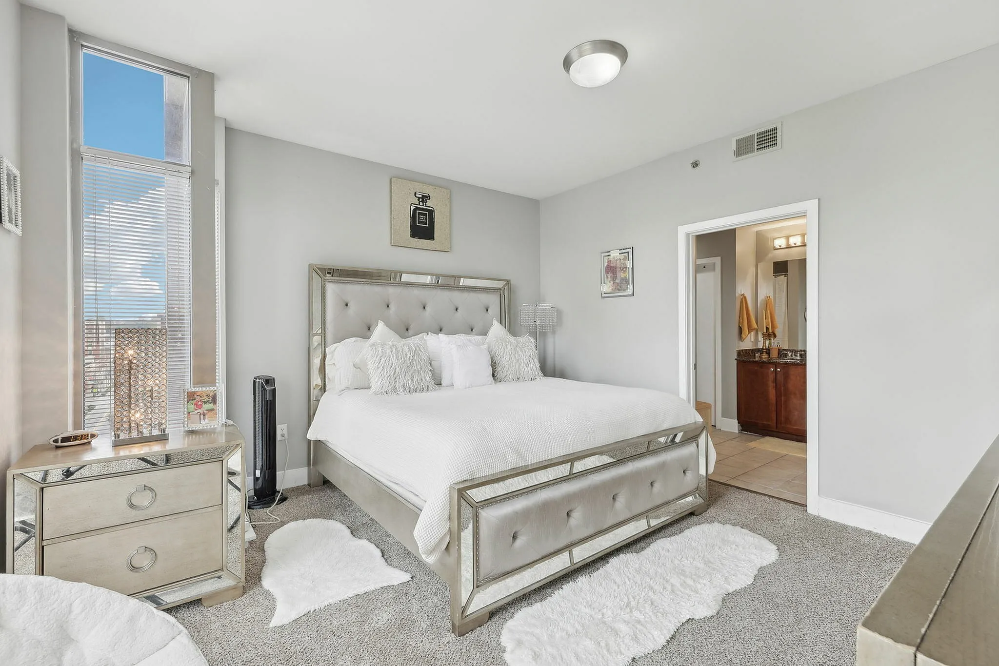 Primary bedroom with large windows, plush carpeting, and mirrored furniture.