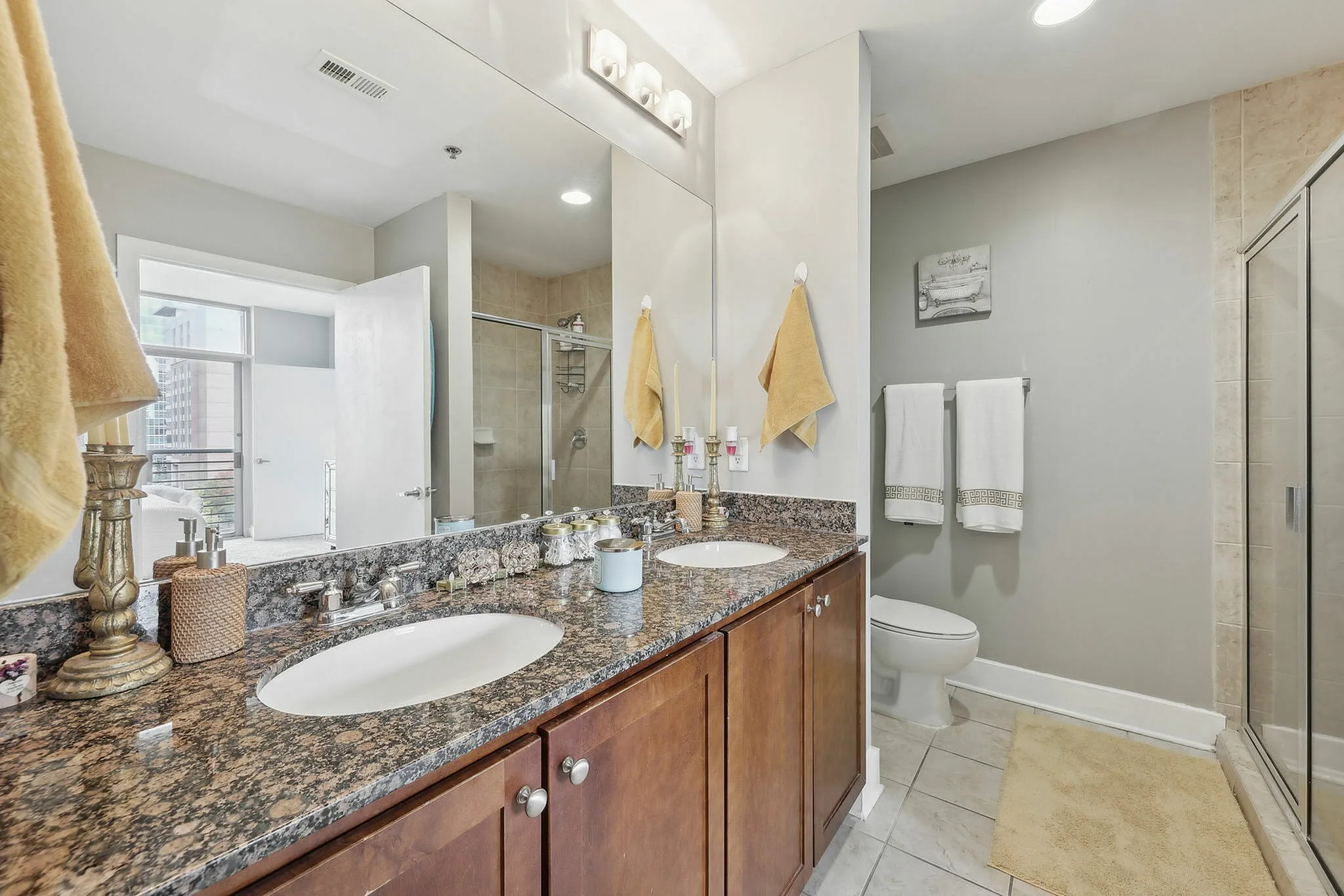 Spacious bathroom featuring double vanity, granite countertops, and walk-in glass shower