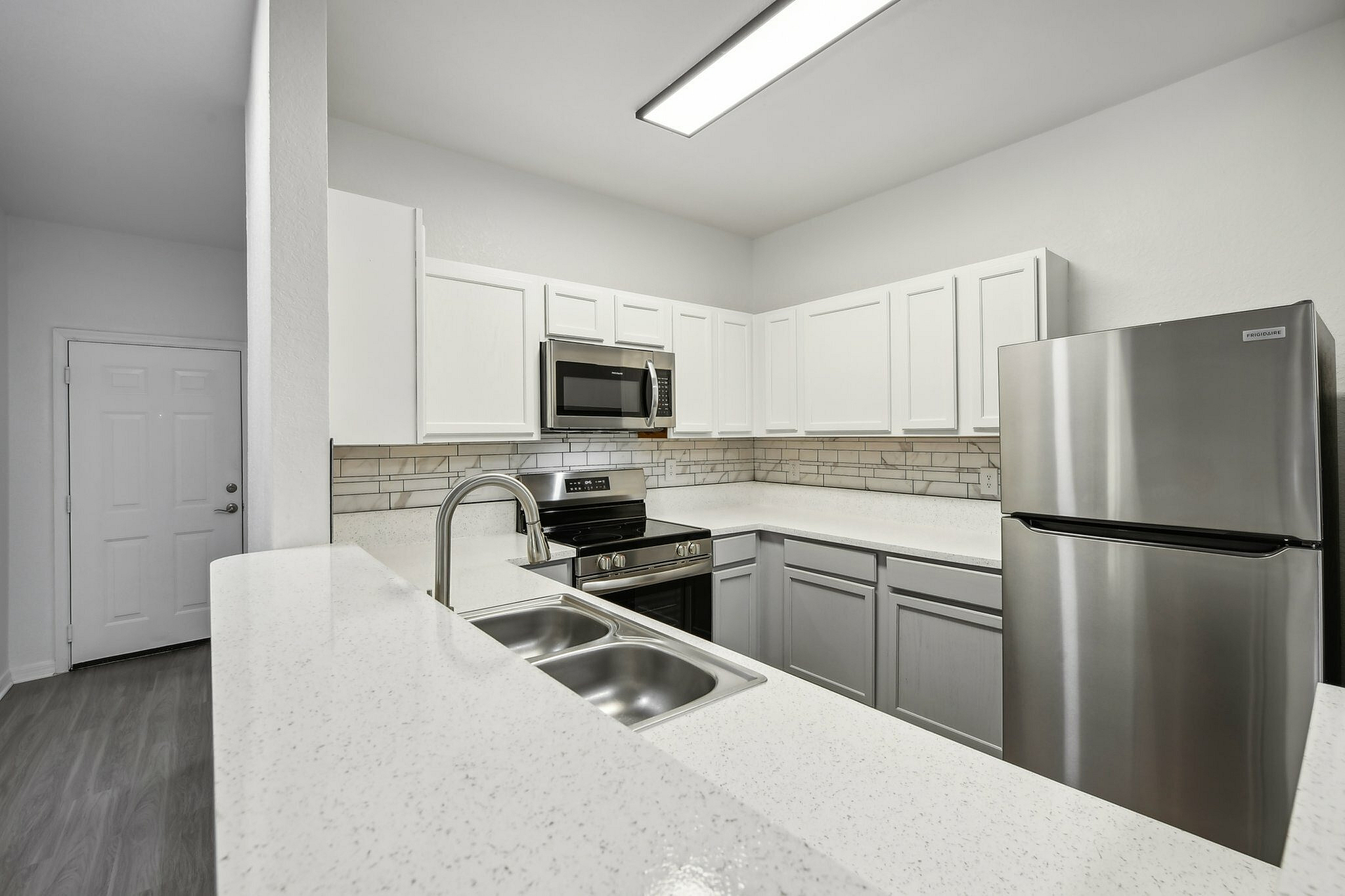 interior pic of deluxe kitchen unit with gray planking and white walls, stainless steel appliances and backsplash