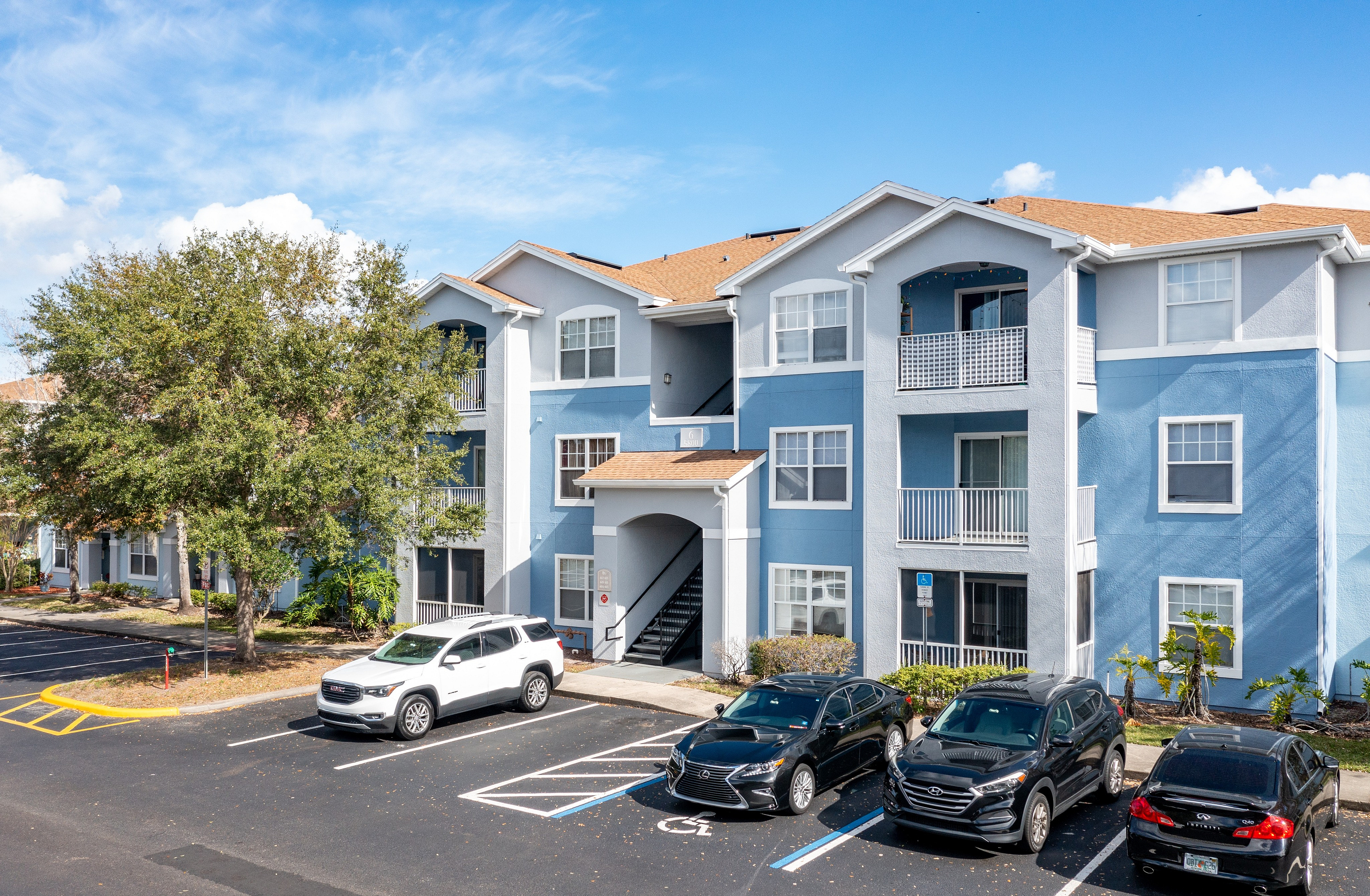 Front view of Village at Lake Pointe apartment building and resident parking.