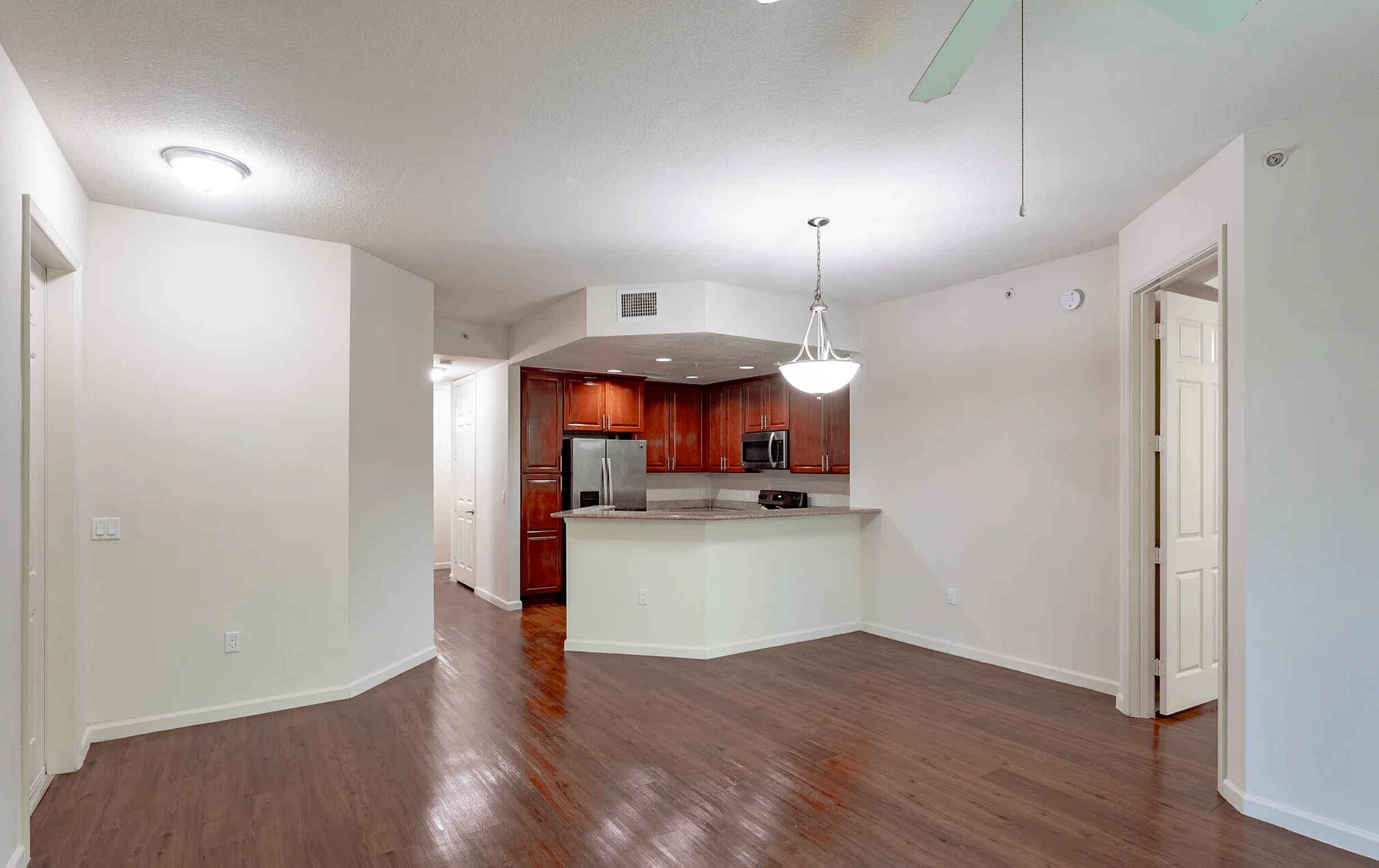 Elegant open-concept apartment with sleek hardwood flooring, modern kitchen, and inviting dining area.
