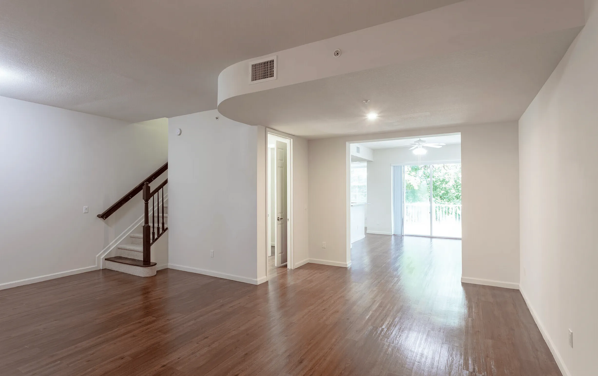 Remodeled split-level apartment with hardwood flooring, open layout, staircase, and balcony view.