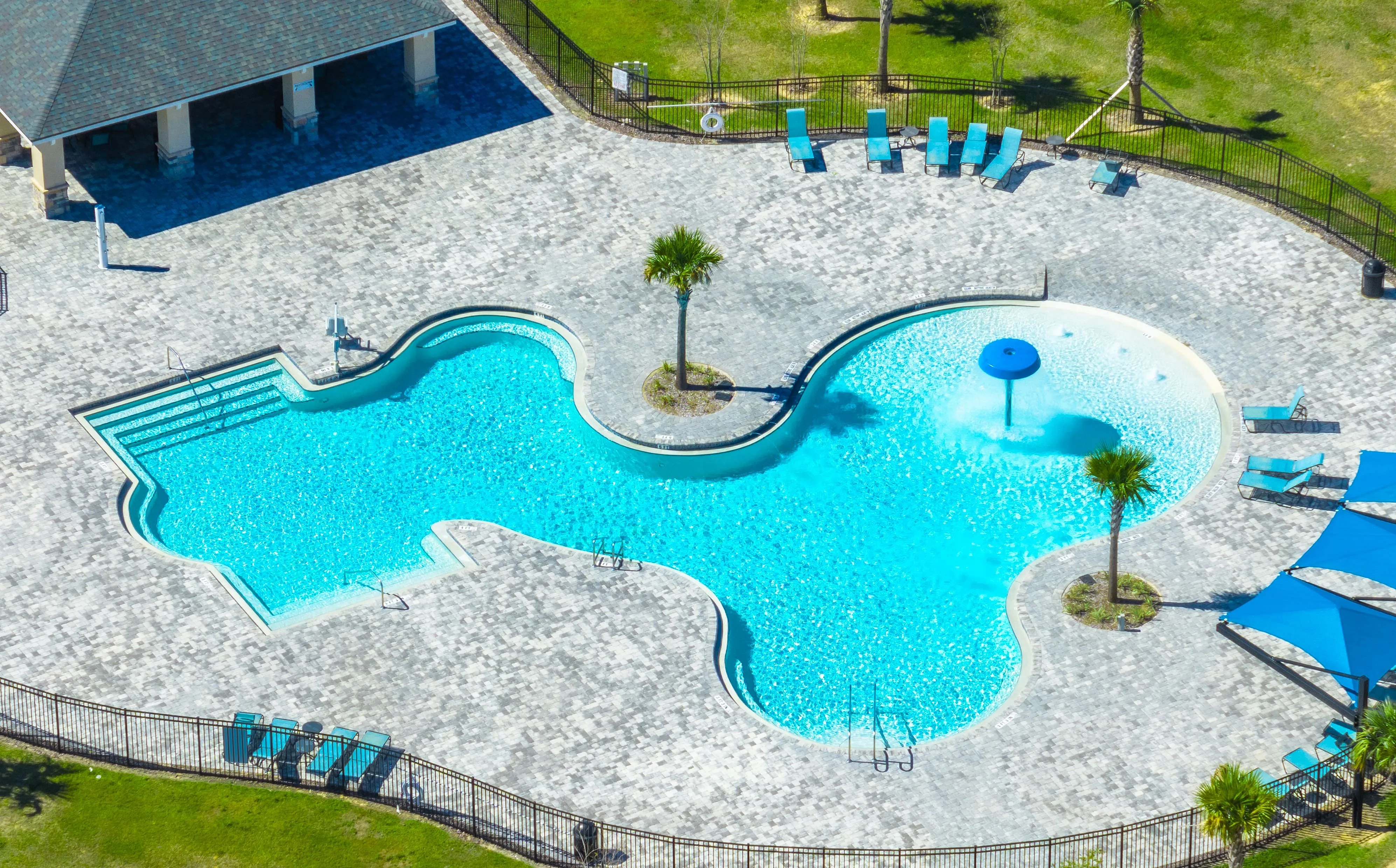 Resort-style pool with splash pad and shaded seating.
