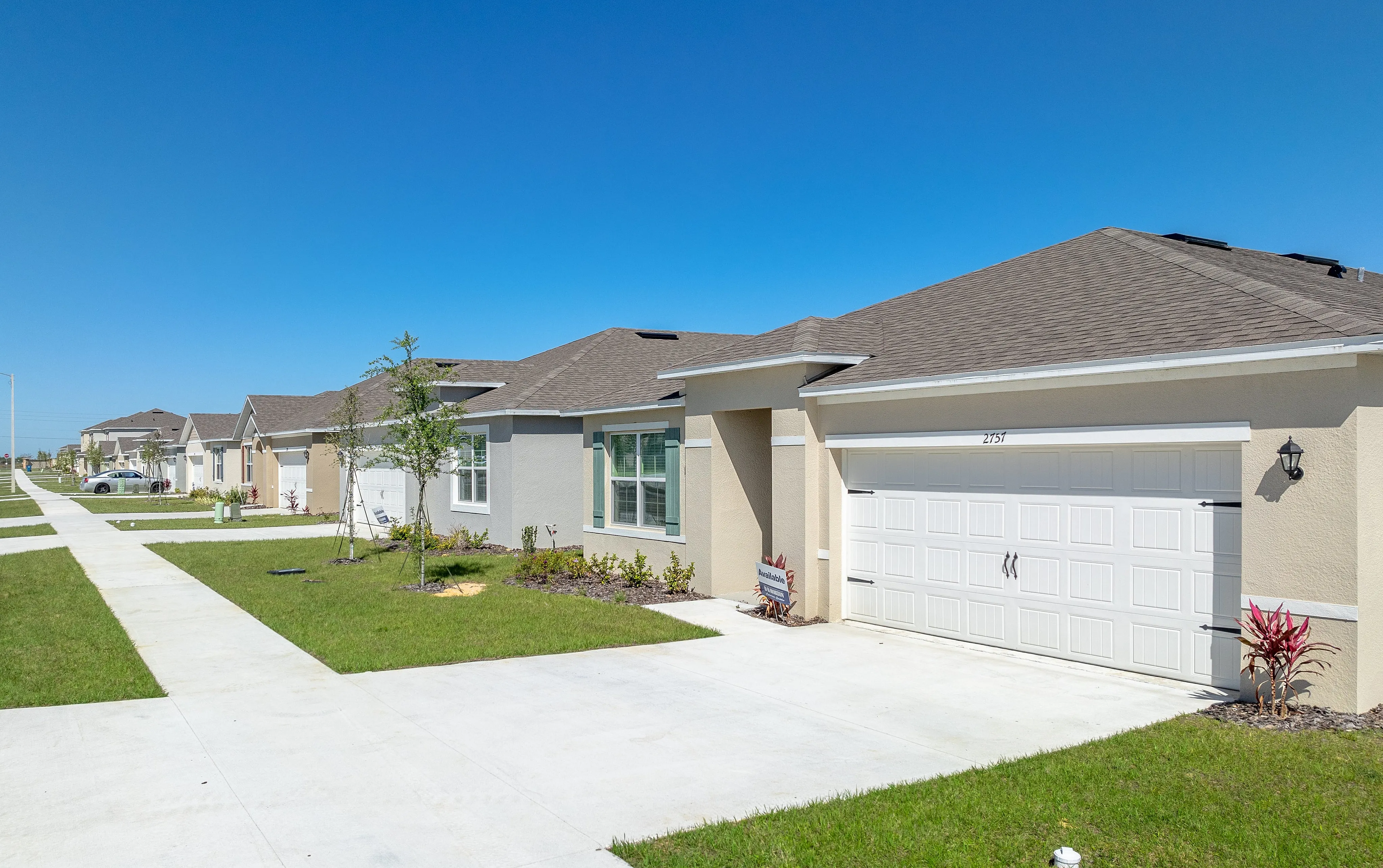 Charming suburban neighborhood with modern beige homes, neat lawns, and tranquil blue skies.