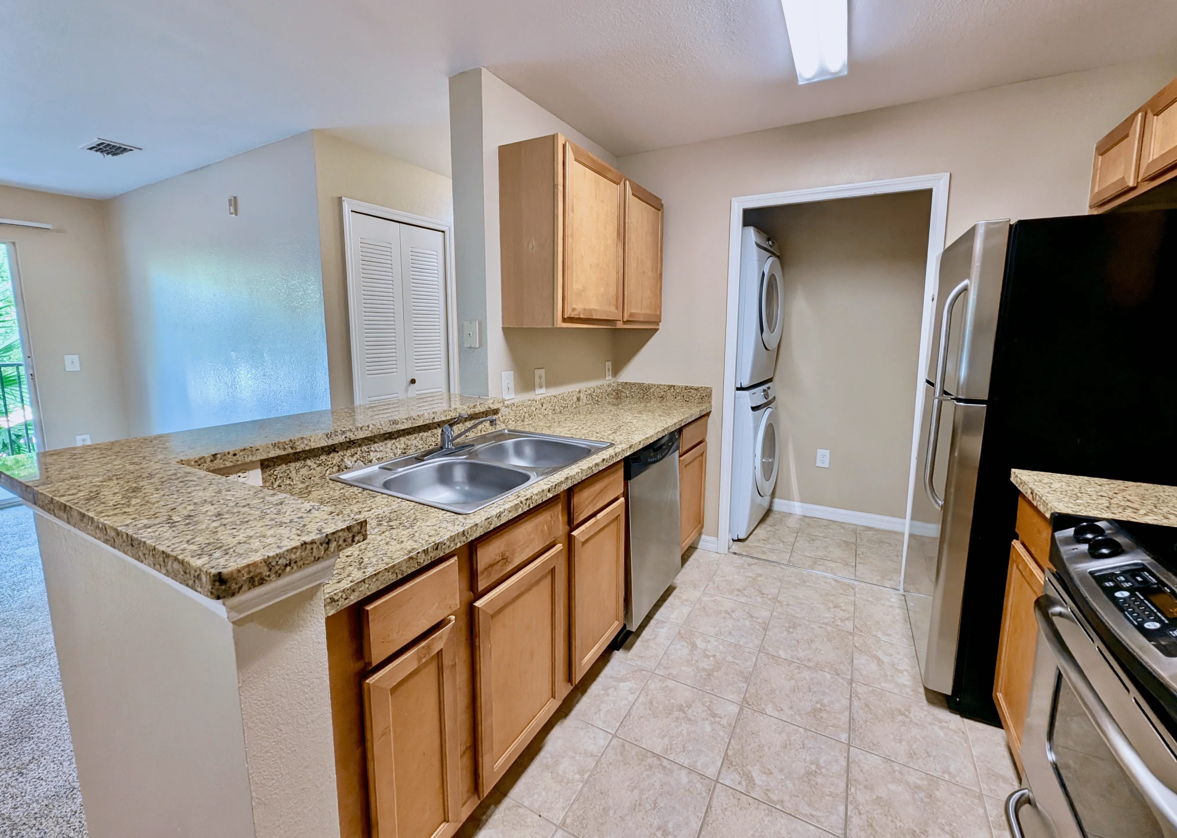 Modern kitchen with granite countertops, stainless steel appliances, and in-unit laundry for convenient living.