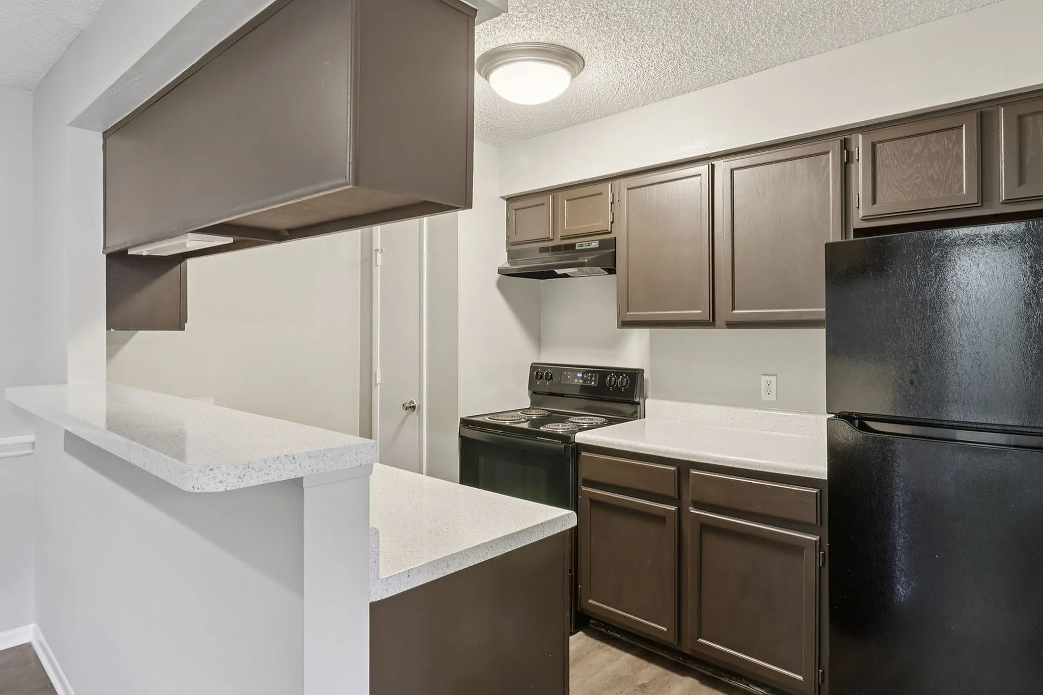 Modern kitchen with sleek brown cabinetry, elegant countertops, and black appliances.