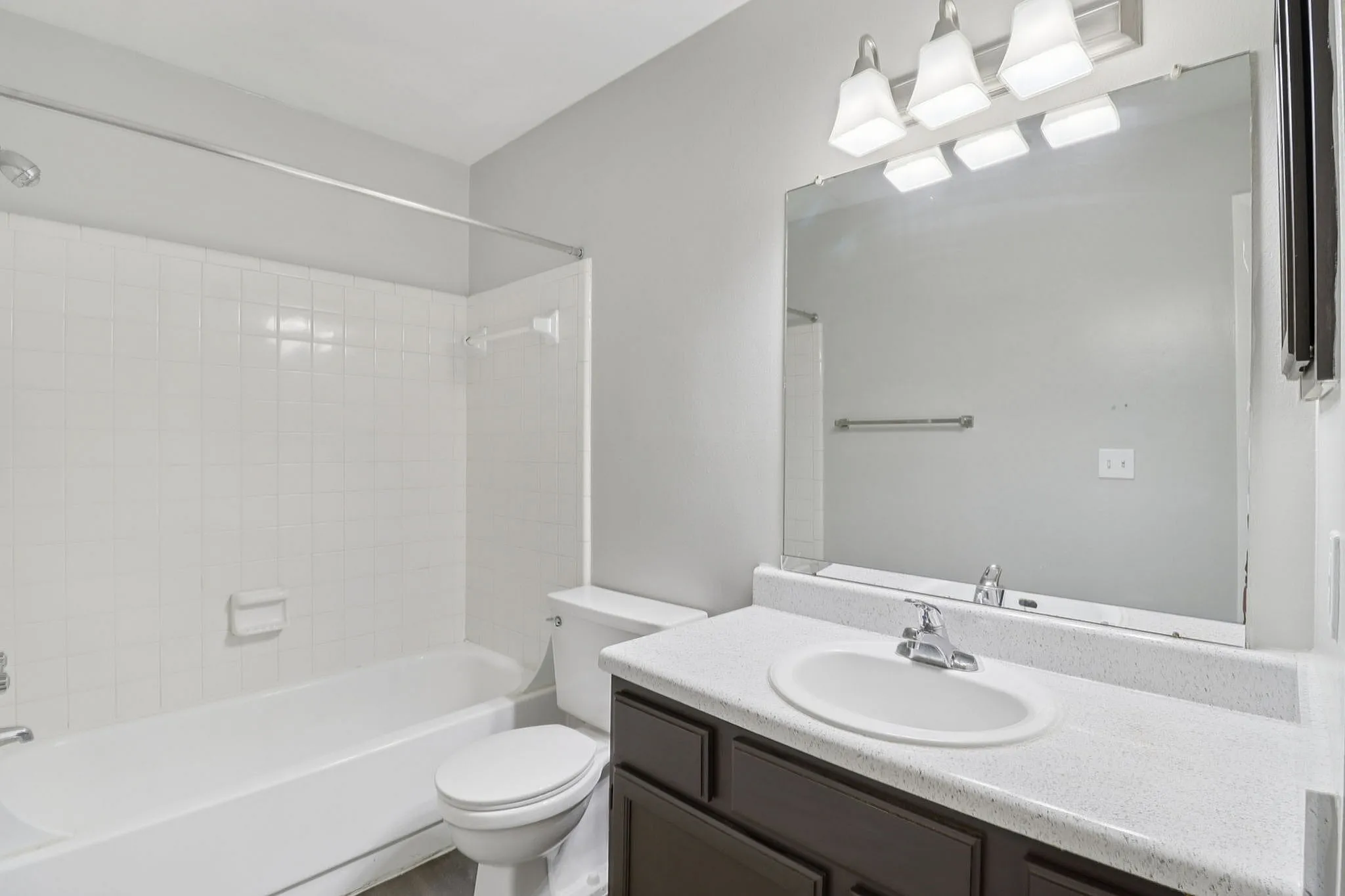 Modern and bright bathroom featuring sleek fixtures, a pristine bathtub, and a spacious vanity mirror, perfect for relaxation.