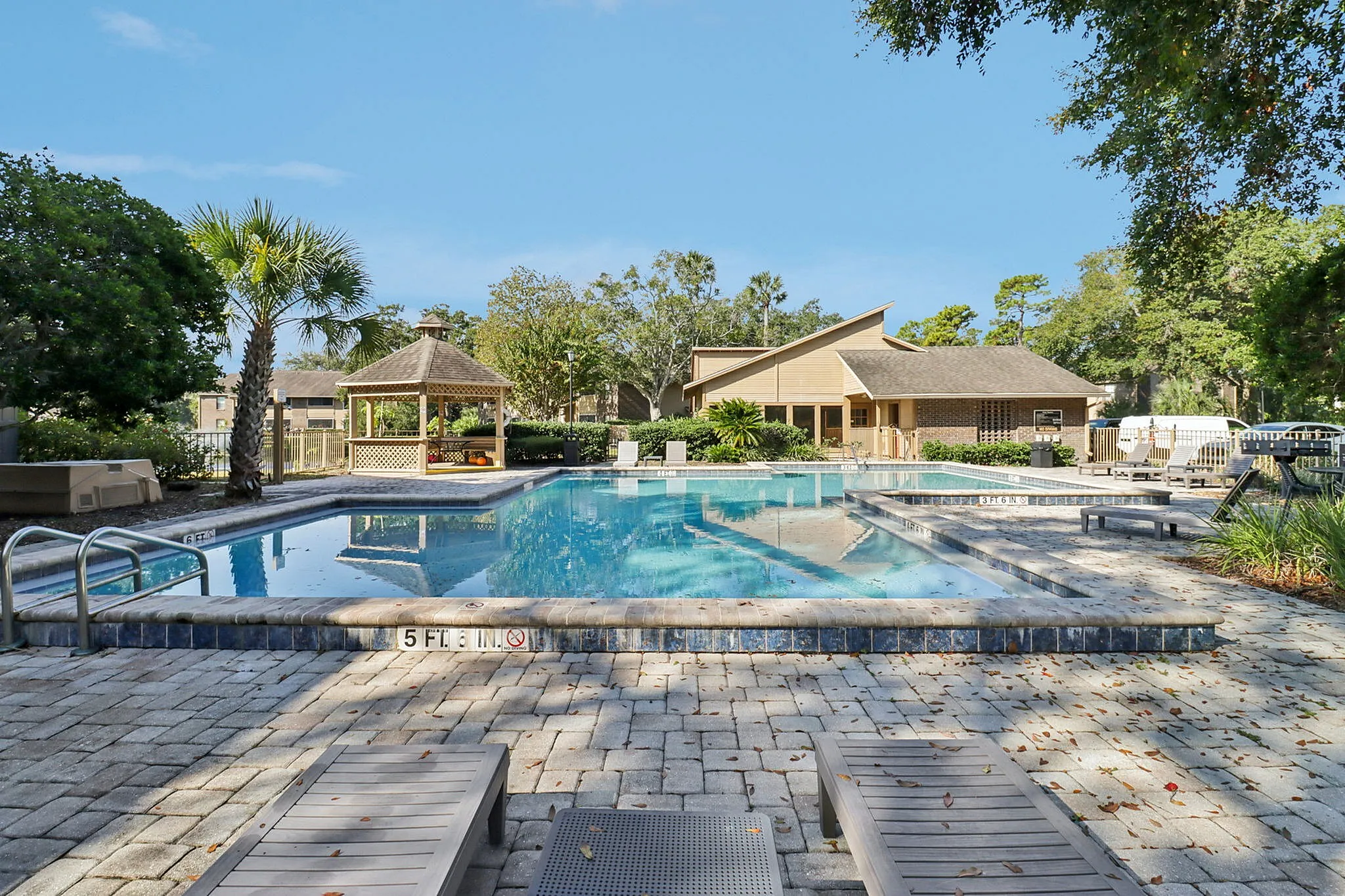 Inviting outdoor pool area with lush greenery, sun loungers, and a charming wooden gazebo, ideal for relaxation and leisure.