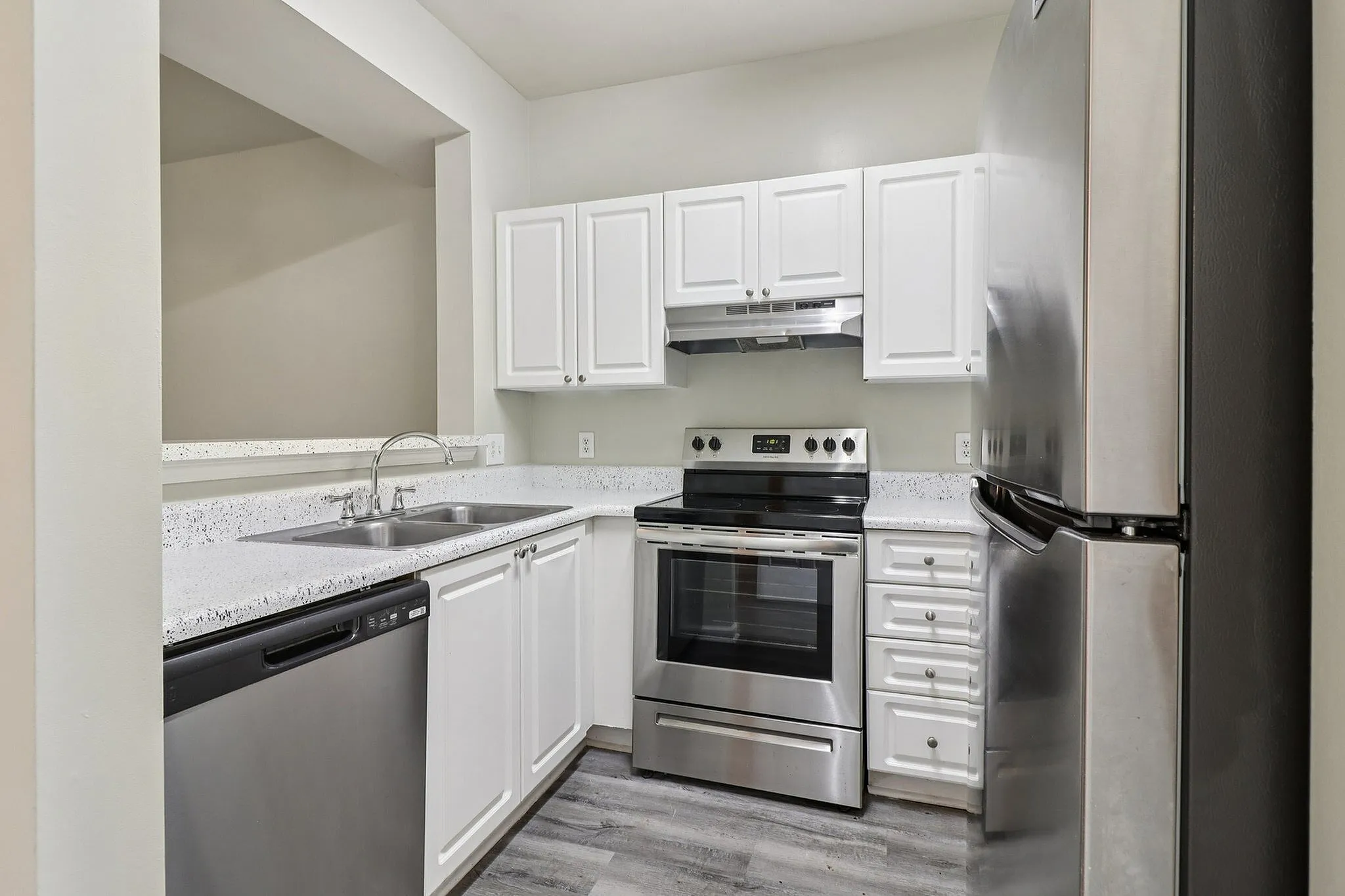 Modern kitchen with sleek stainless steel appliances, elegant white cabinetry, and polished countertops.