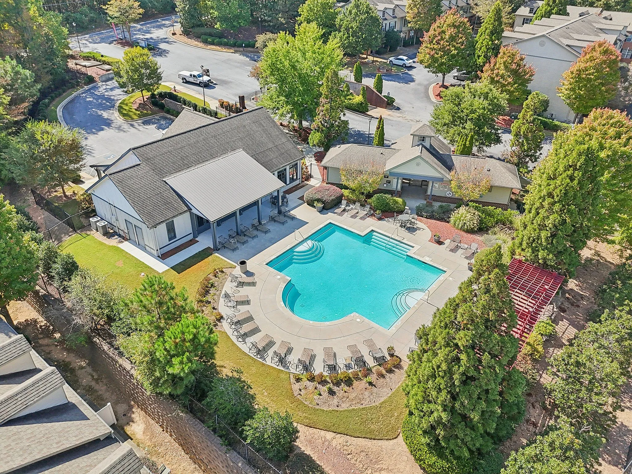 Aerial view of a luxurious residential complex featuring a sparkling swimming pool, lush greenery, and stylish modern buildings, perfect for relaxation and leisure.