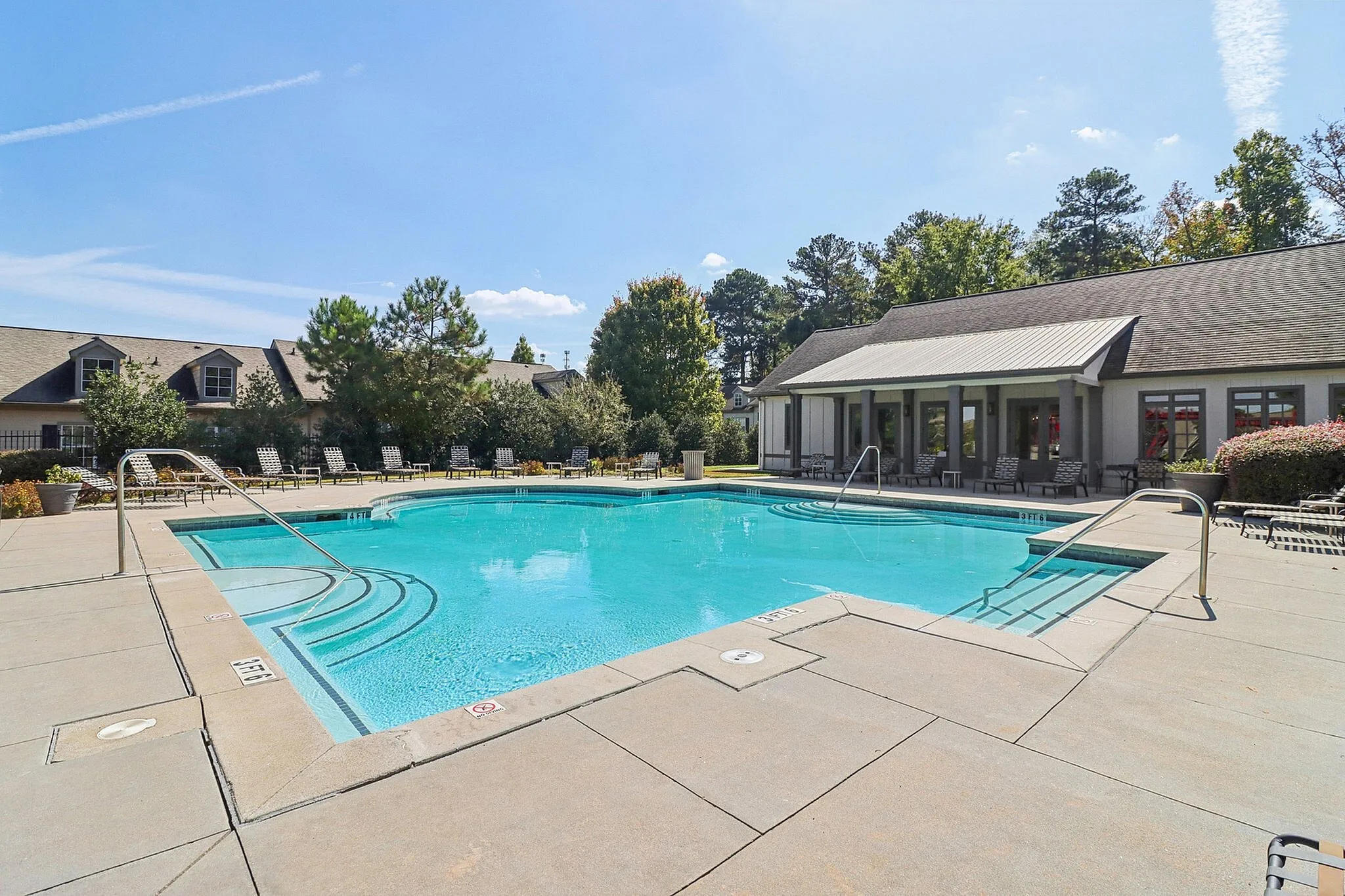 Inviting outdoor pool area with crystal-clear water, surrounded by comfortable seating and lush greenery.