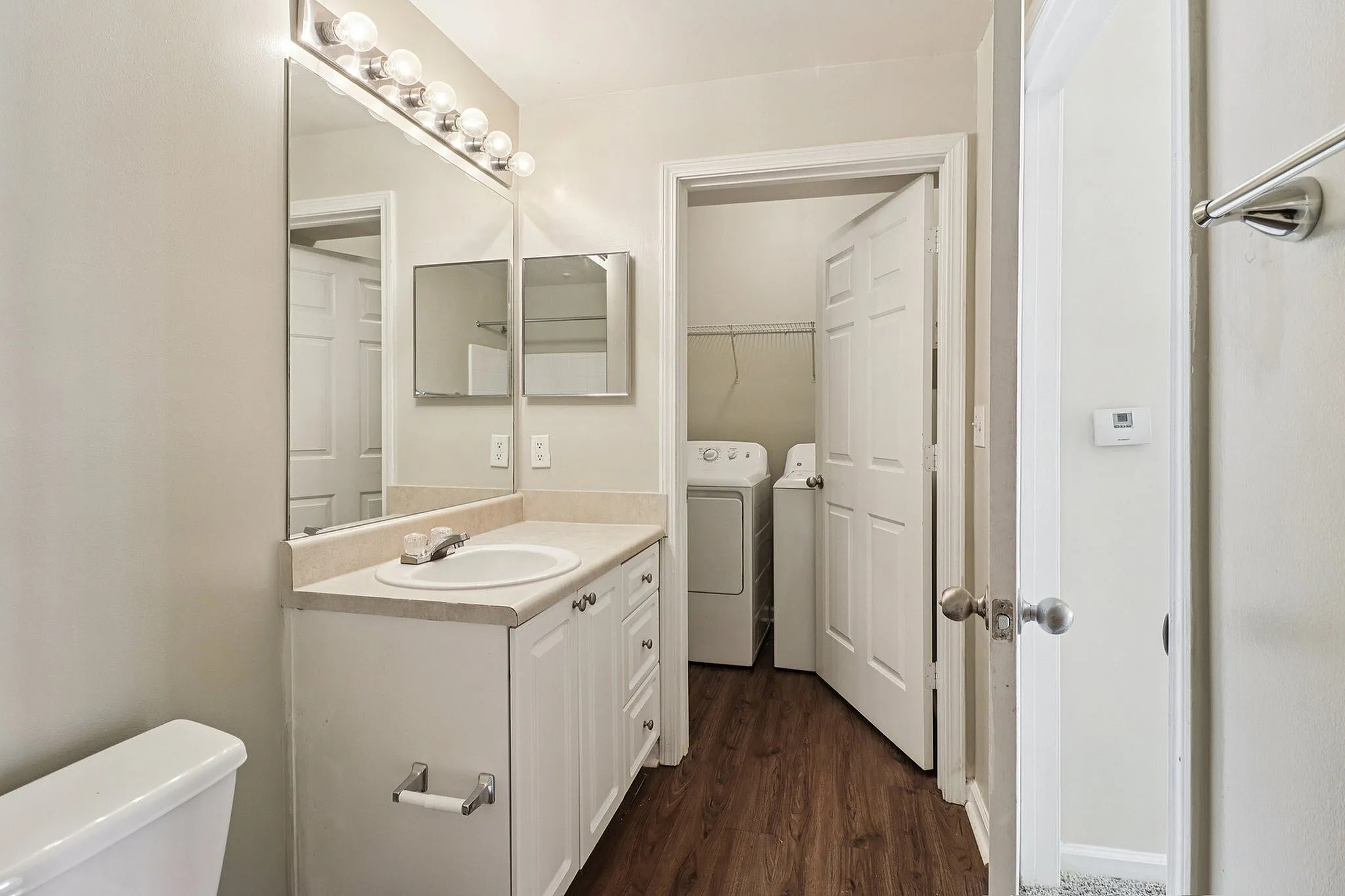 Elegant bathroom featuring a wide mirror, sleek vanity, and convenient in-unit laundry area with washer and dryer.