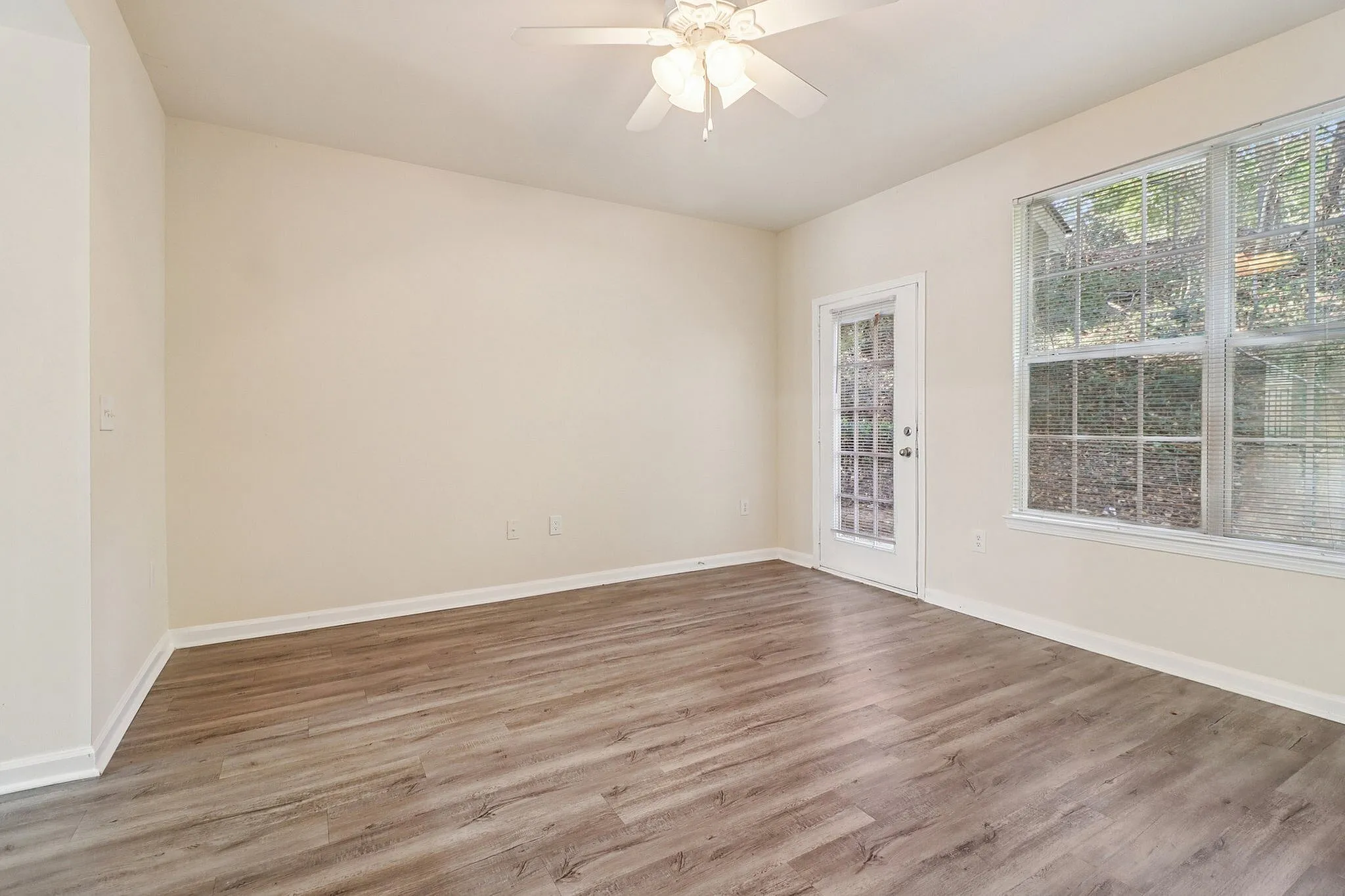 Bright and airy room with sleek hardwood floors, a ceiling fan, and large windows offering scenic views.