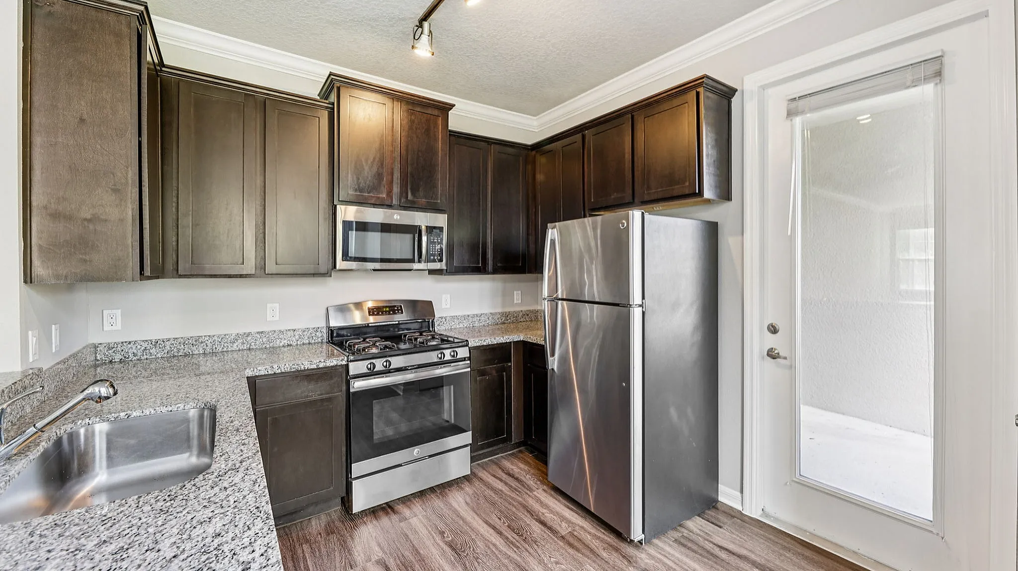 Modern kitchen with sleek stainless steel appliances, dark wood cabinets, and elegant granite countertops.